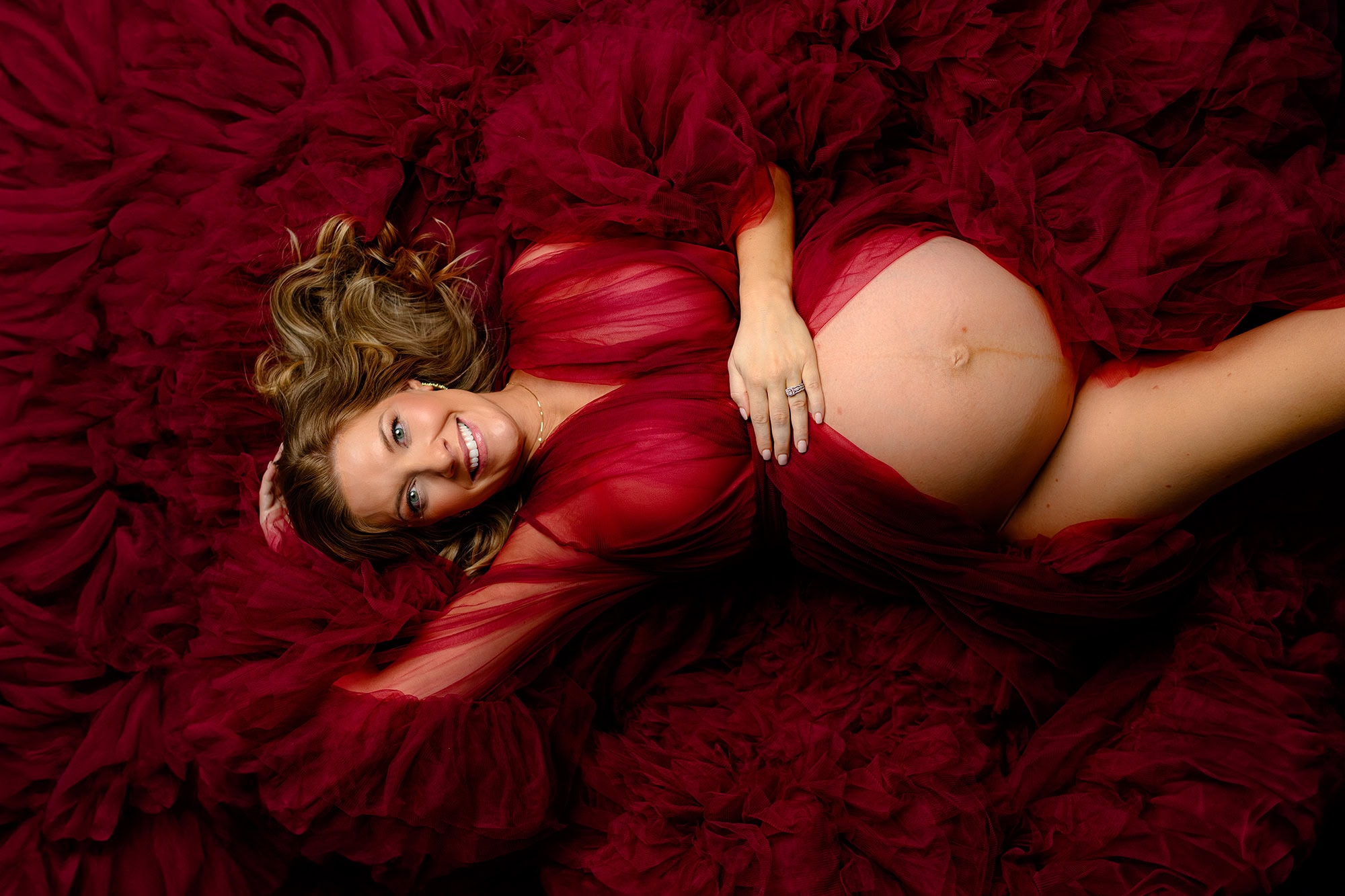 maternity studio photography session of mom to be wearing a red tulle dress