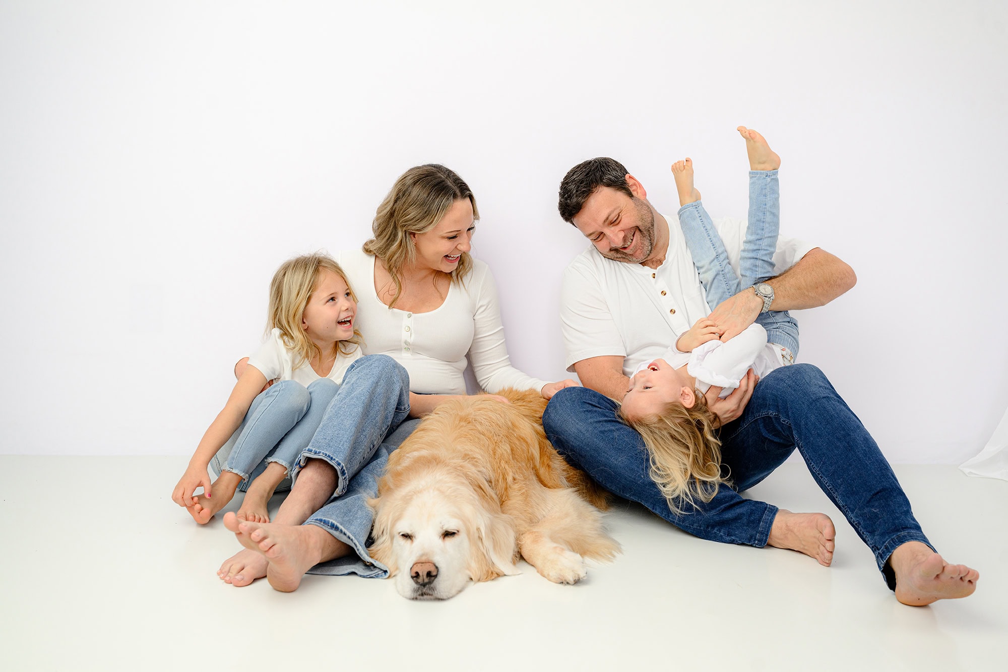 family with golden retriever having fun during studio portraits 