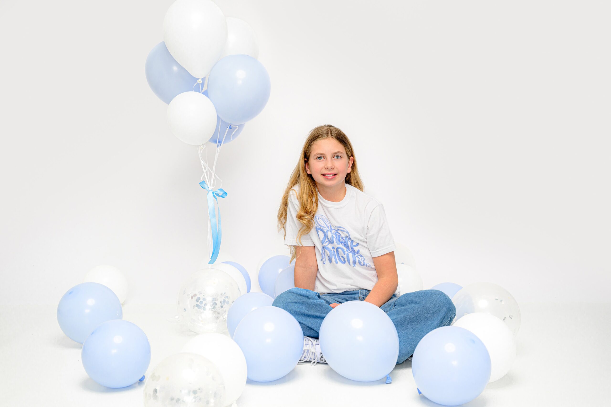 charlotte ten year old girl sits in the floor criss cross with balloons around her