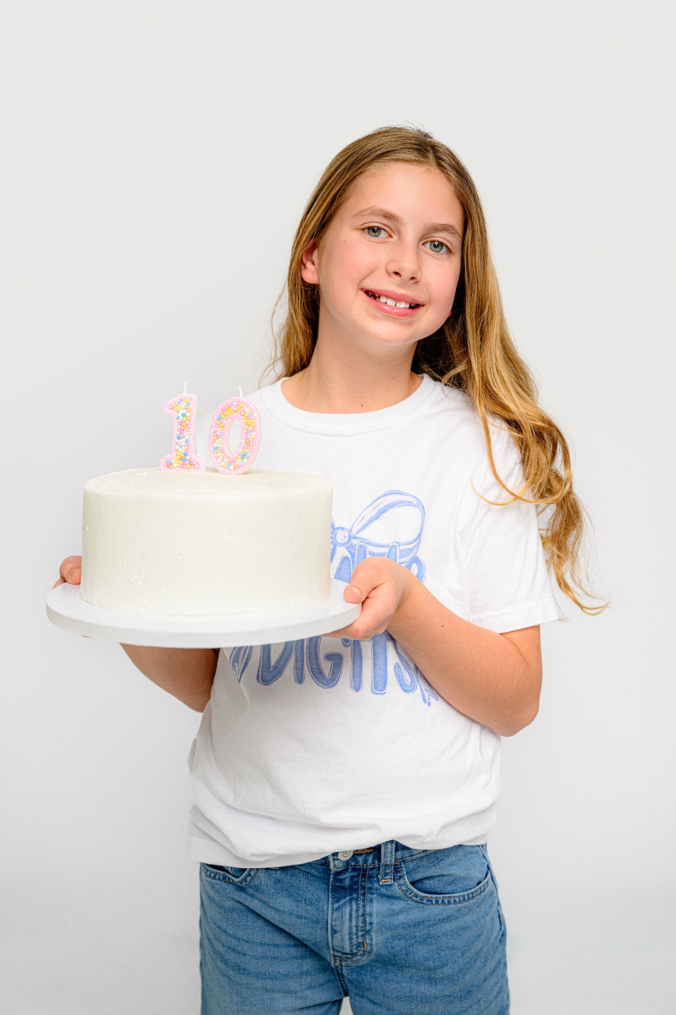 ten year old charlotte girl holding her white birthday cake with candles for her birthday photo session