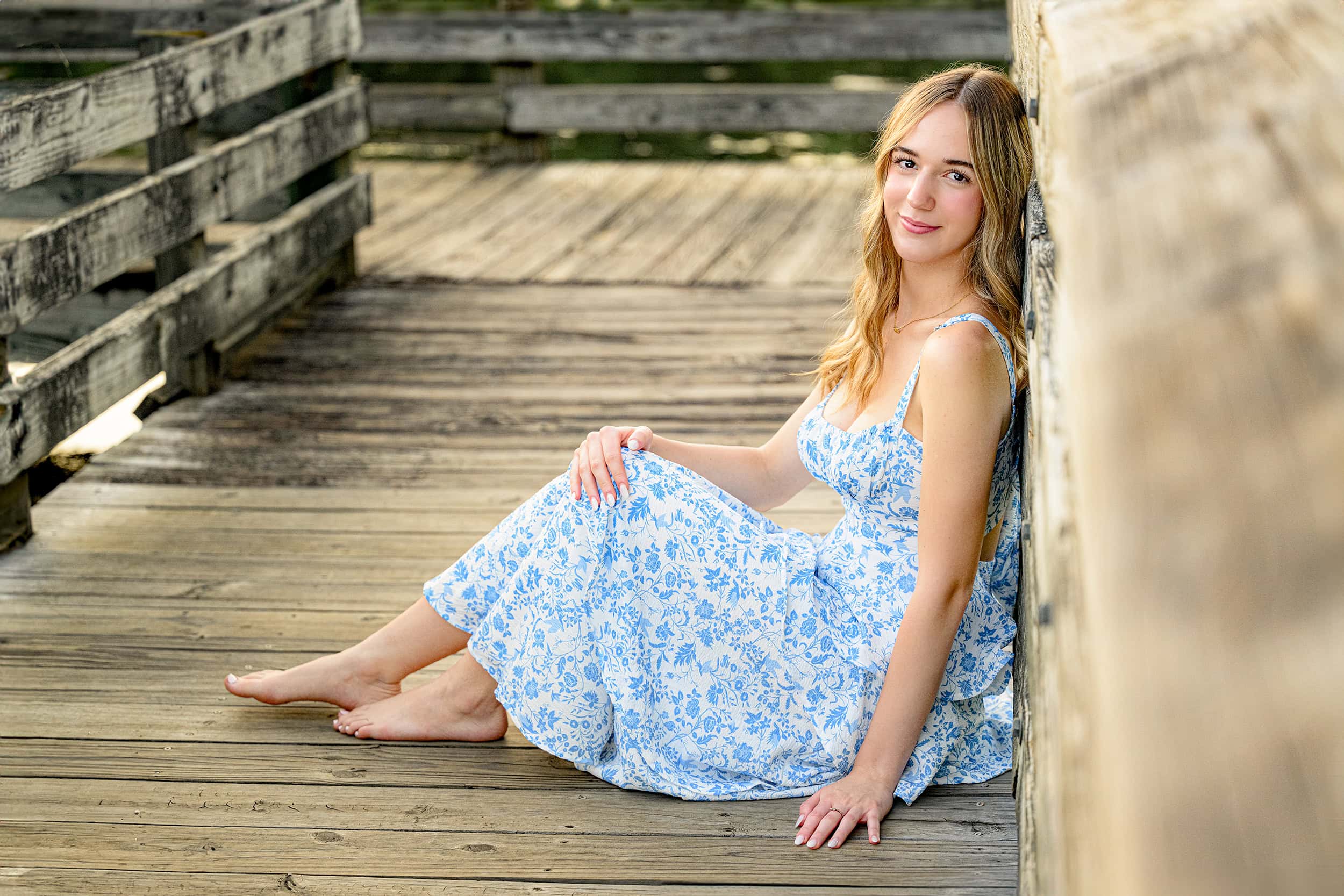 senior sits against a railing at a favorite senior photo location