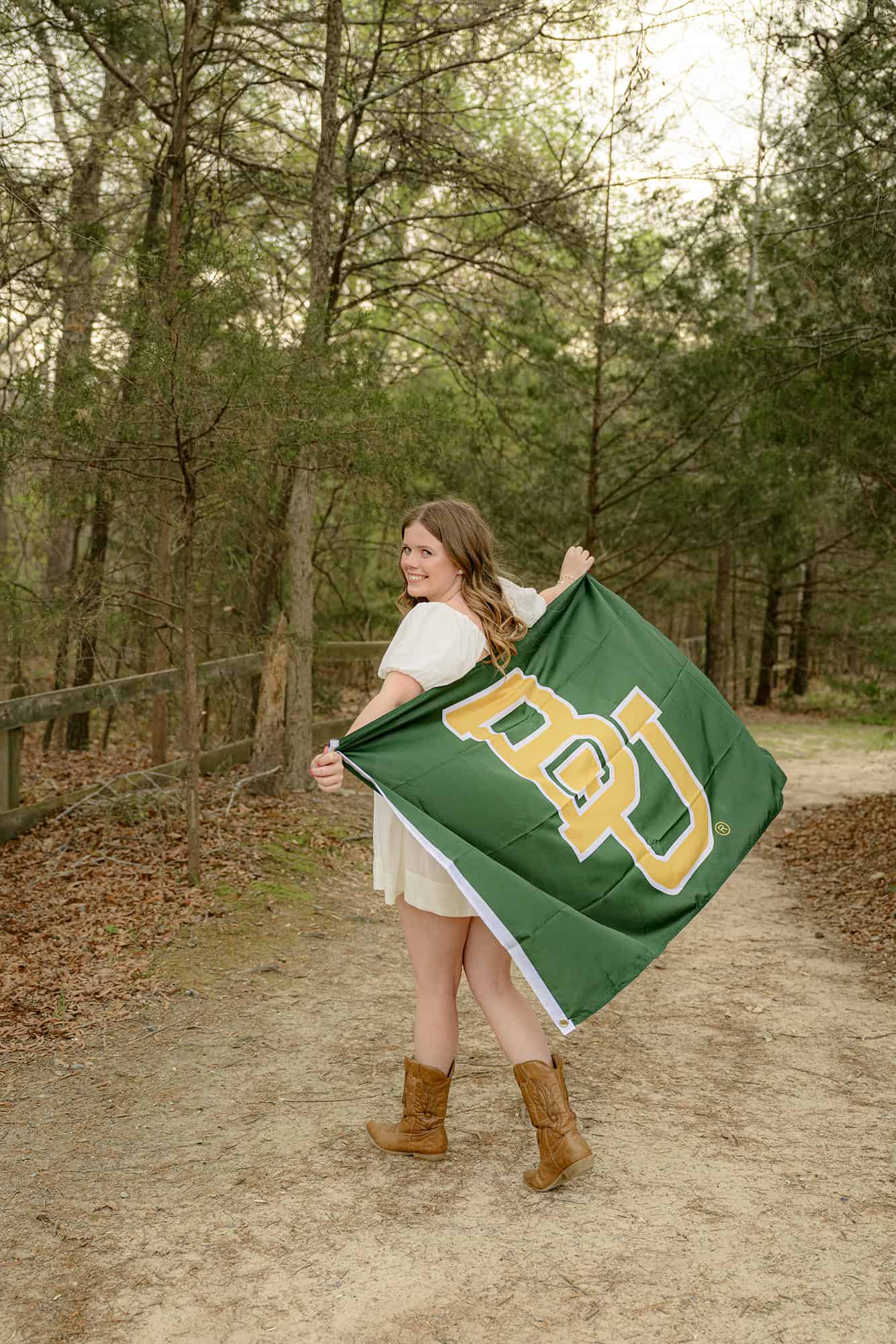 high school grad walks away holding her future college flag as part of her senior portraits