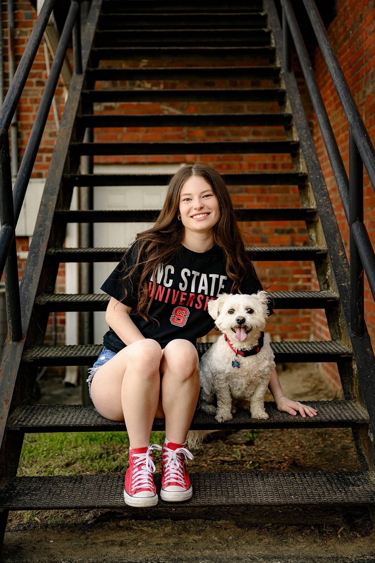 high school senior wearing  nc state college gear t shirt sitting on steps