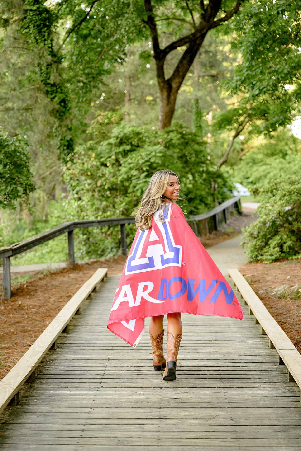 high school senior looks back over her shoulder while walking away with flag draped around her