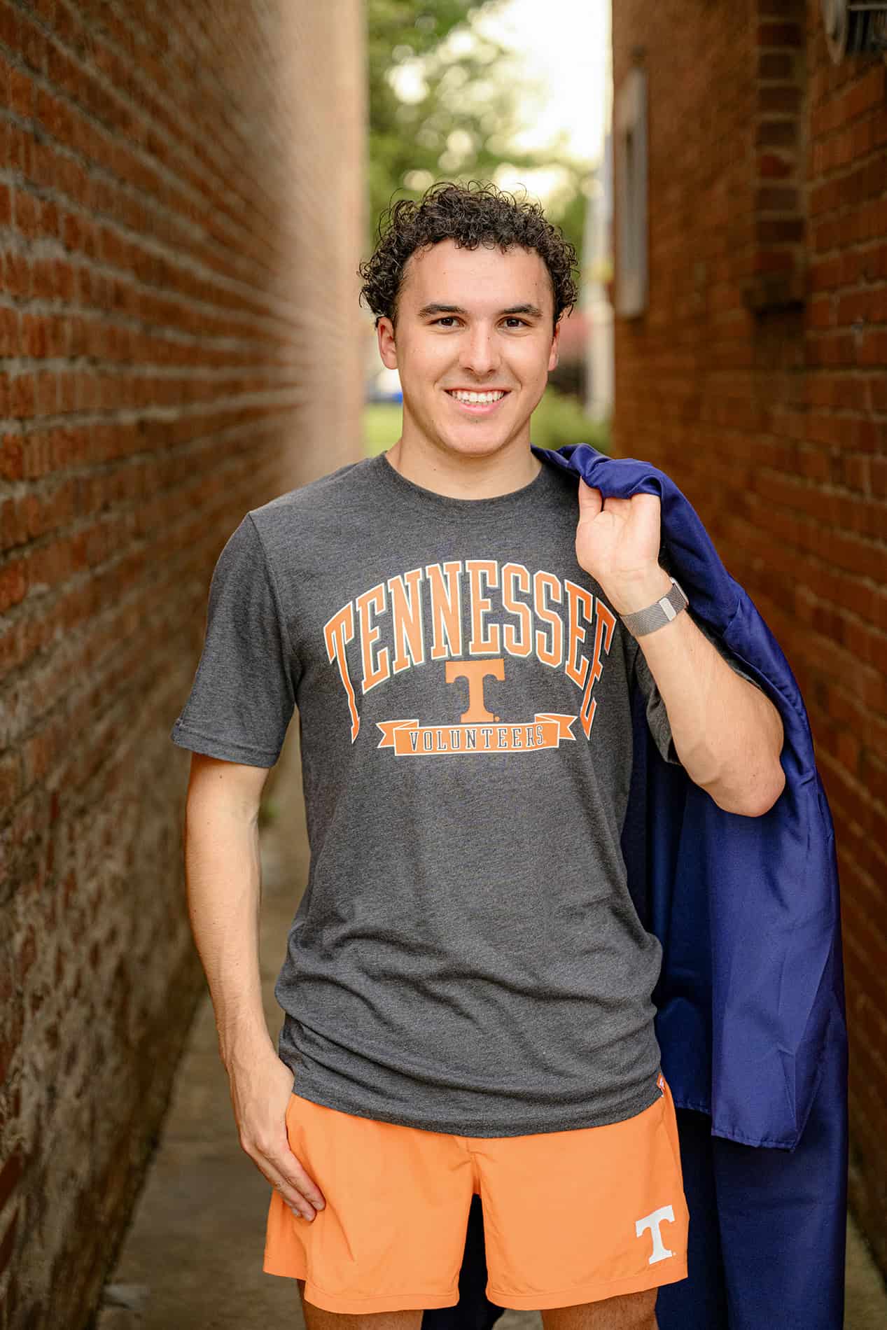 Future UT attendee wearing t shirt to celebrate his new school and holding his high school graduation gown