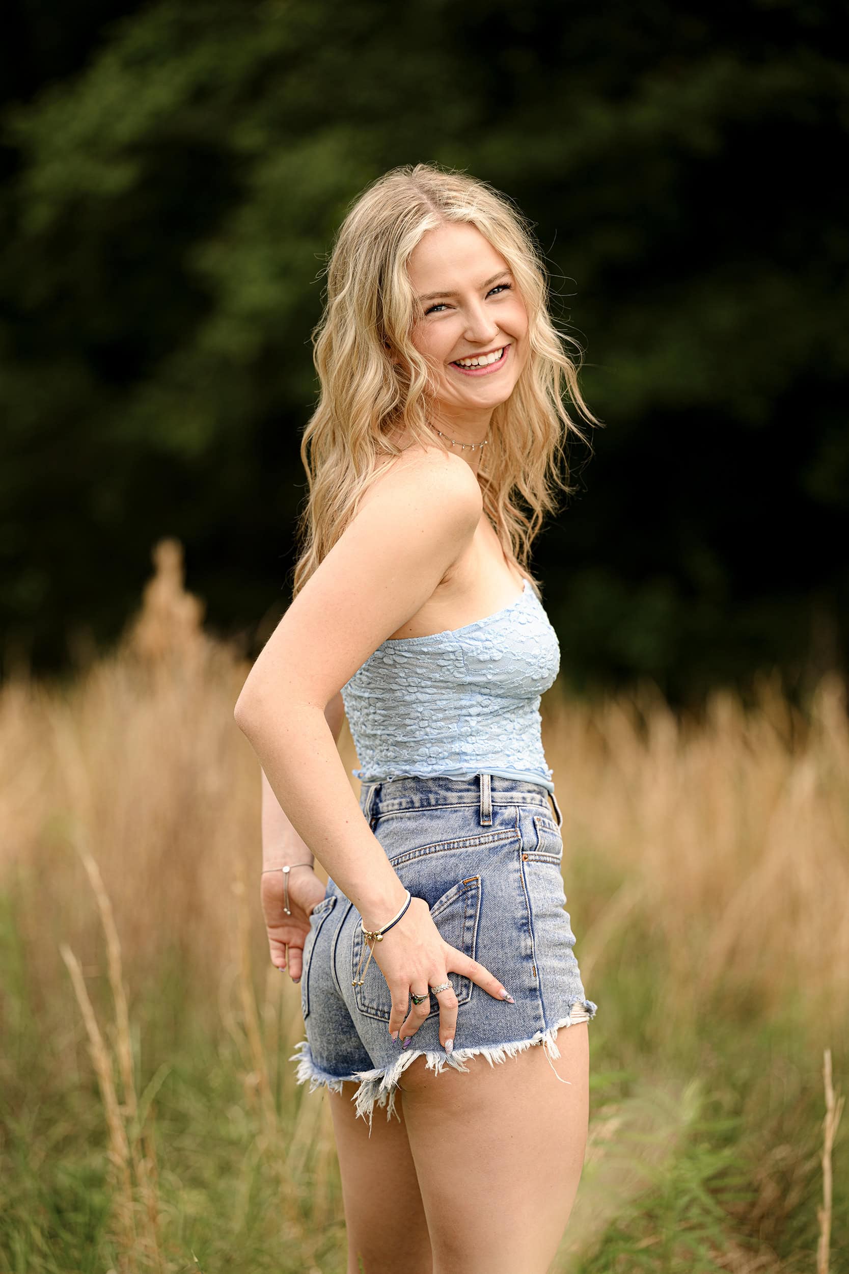 senior photo of blonde graduate smiling as she looks back over her shoulder