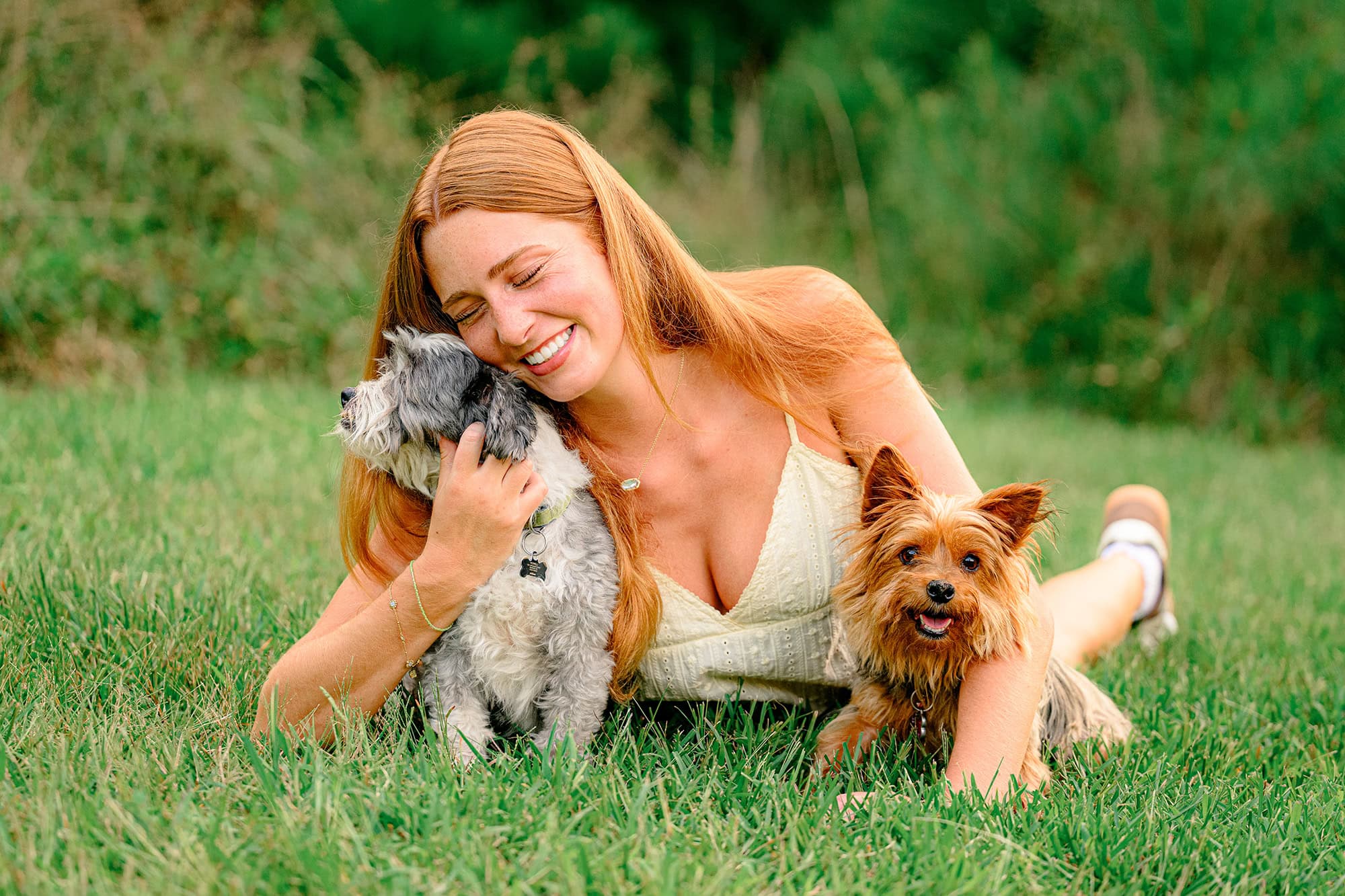 Natural smile as this charlotte graduate hugs her puppies in her senior portraits