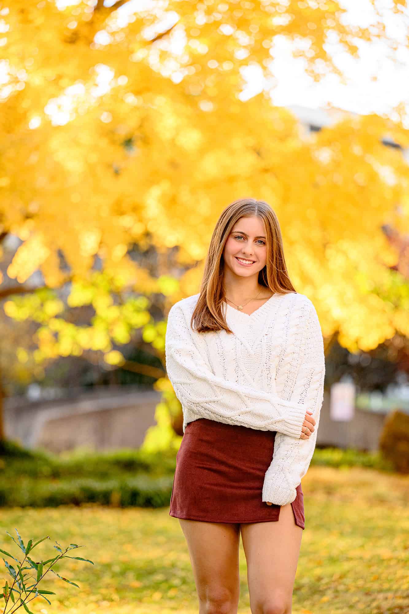 uptown fall trees are highlighted in the photos of this senior wearing a neutral outfit in her senior photos