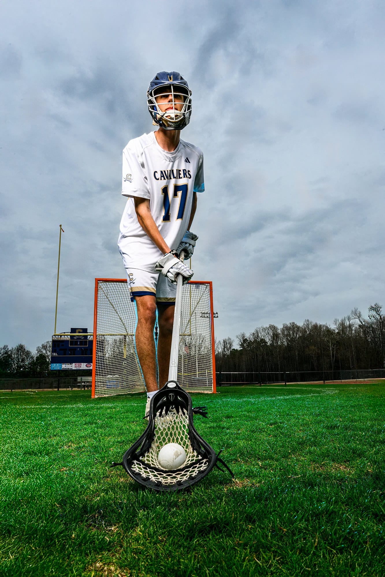 cuthbertson senior lacrosse player holds ball in his stick on a charlotte field with a lacrosse goal behind him