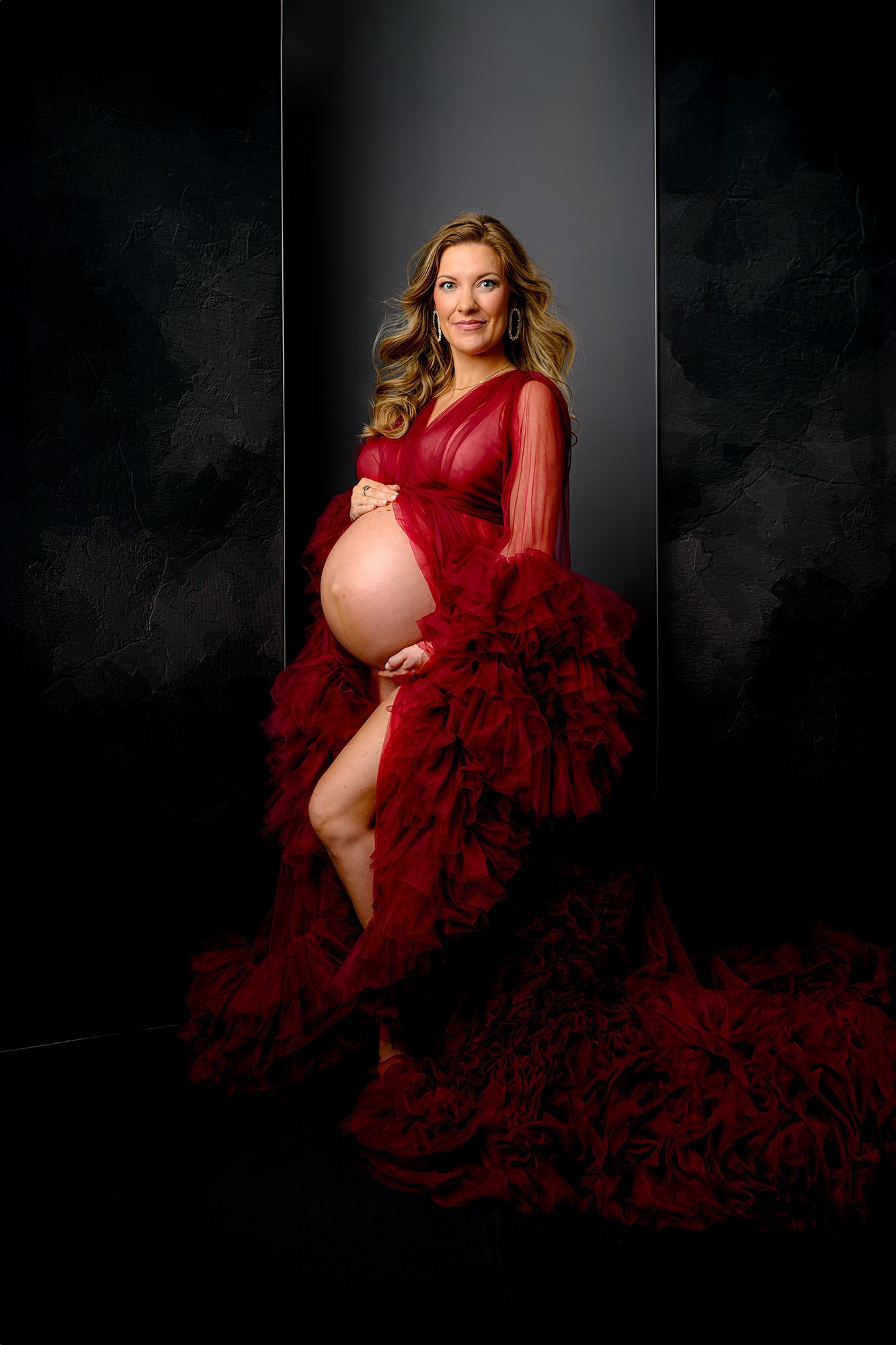 mom to be dressed in a red maternity tulle dress with glam makeup