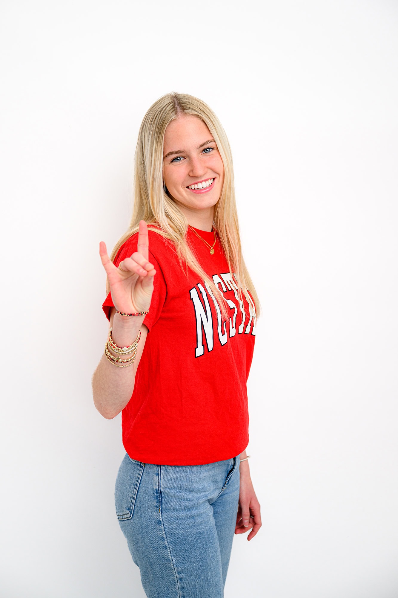 blonde charlotte high school student doing the wolfpack sign wearing a red shirt celebrating her future college decision