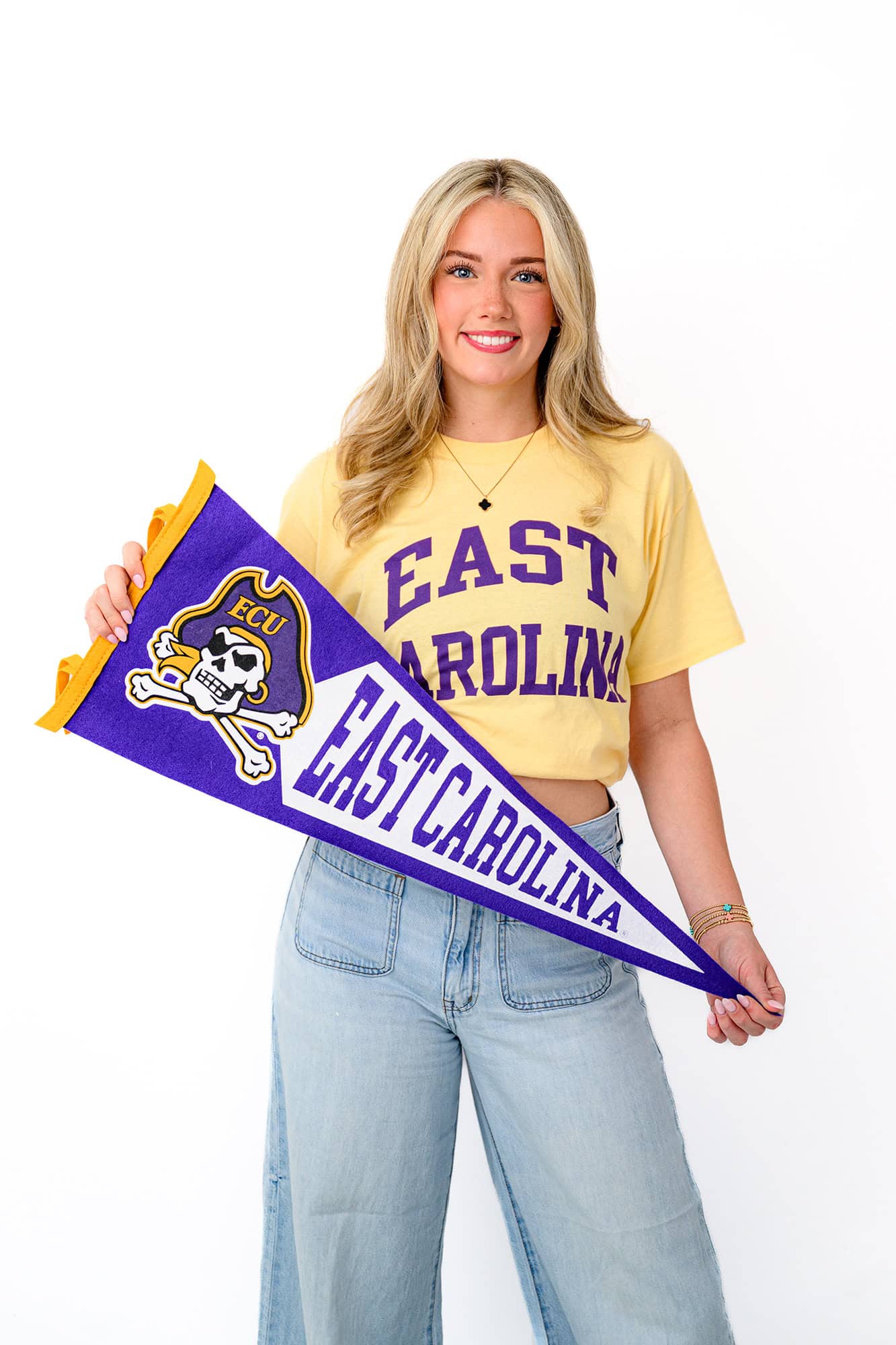 blonde charlotte graduate stands holding her future ECU college pennant