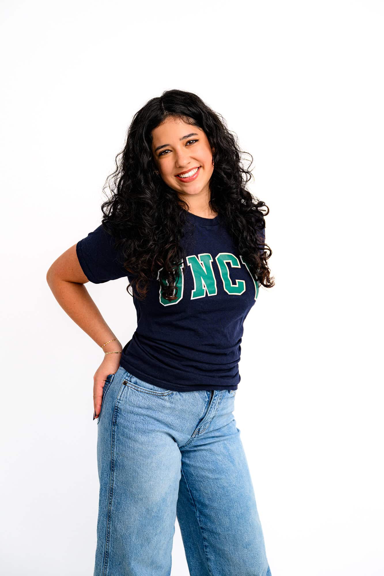 high school senior standing with her hands in her back pockets wearing a UNCW shirt celebrating her college decision