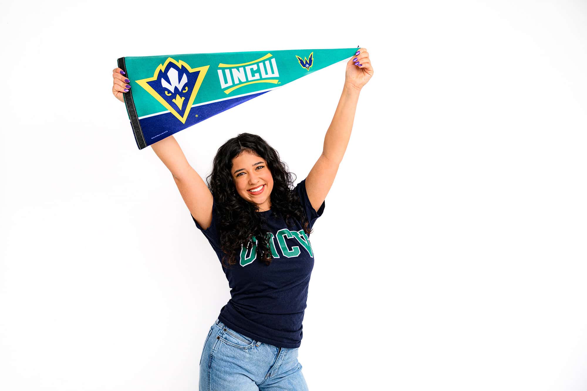 Dark hair future college student wearing a UNCW shirt holding a pennant