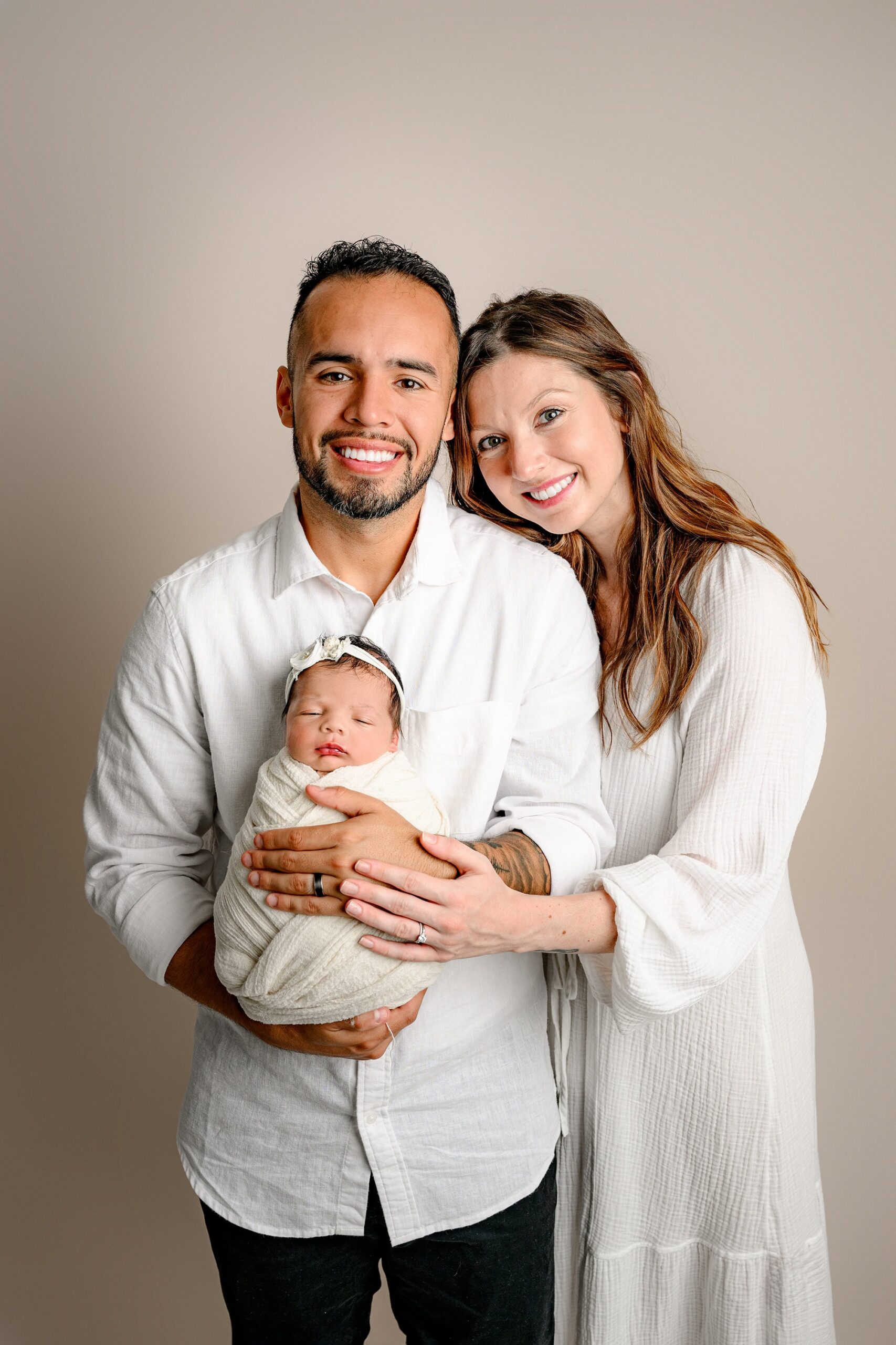 dad holds baby with mom beside him for newborn family photos