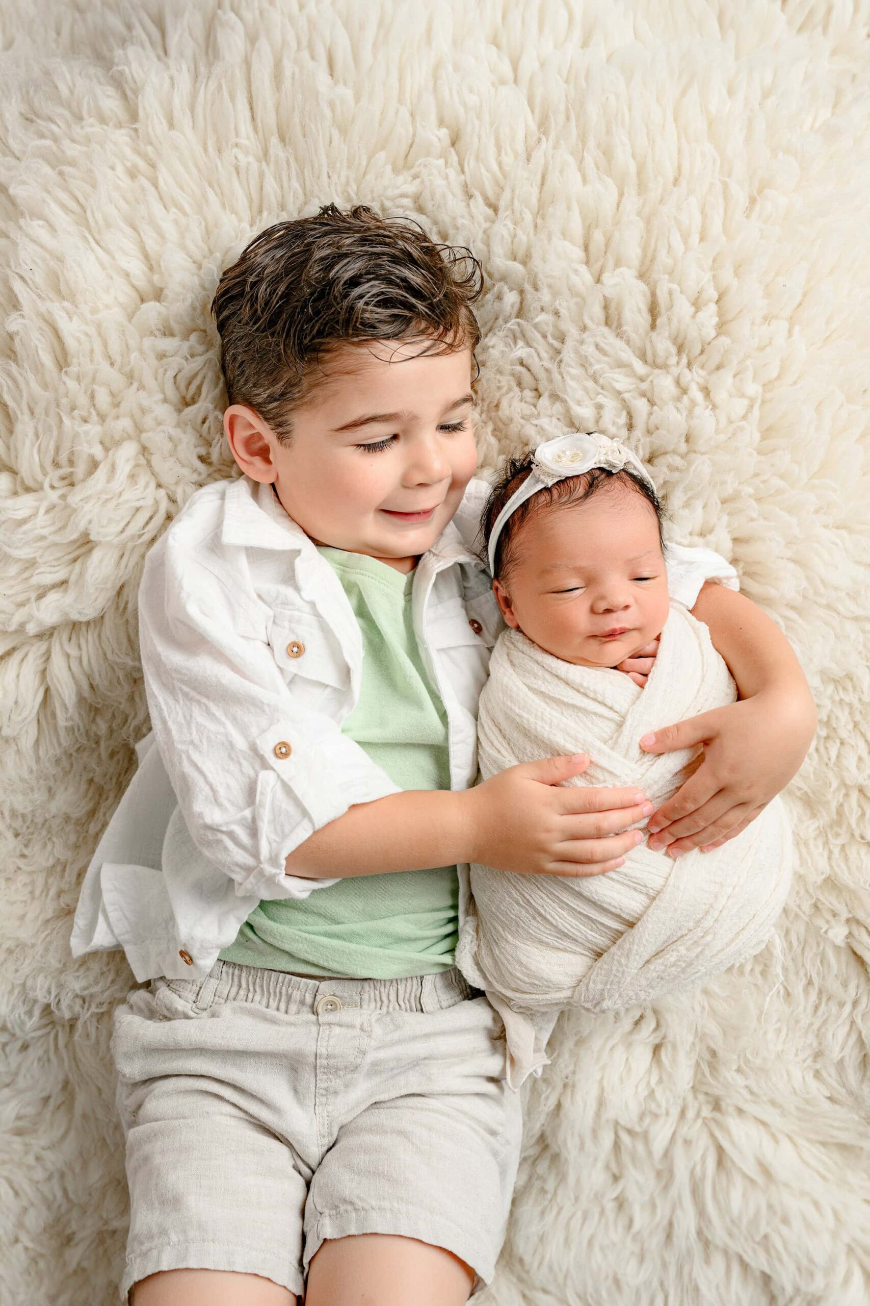 three year old brother holds his newborn sister for family photos