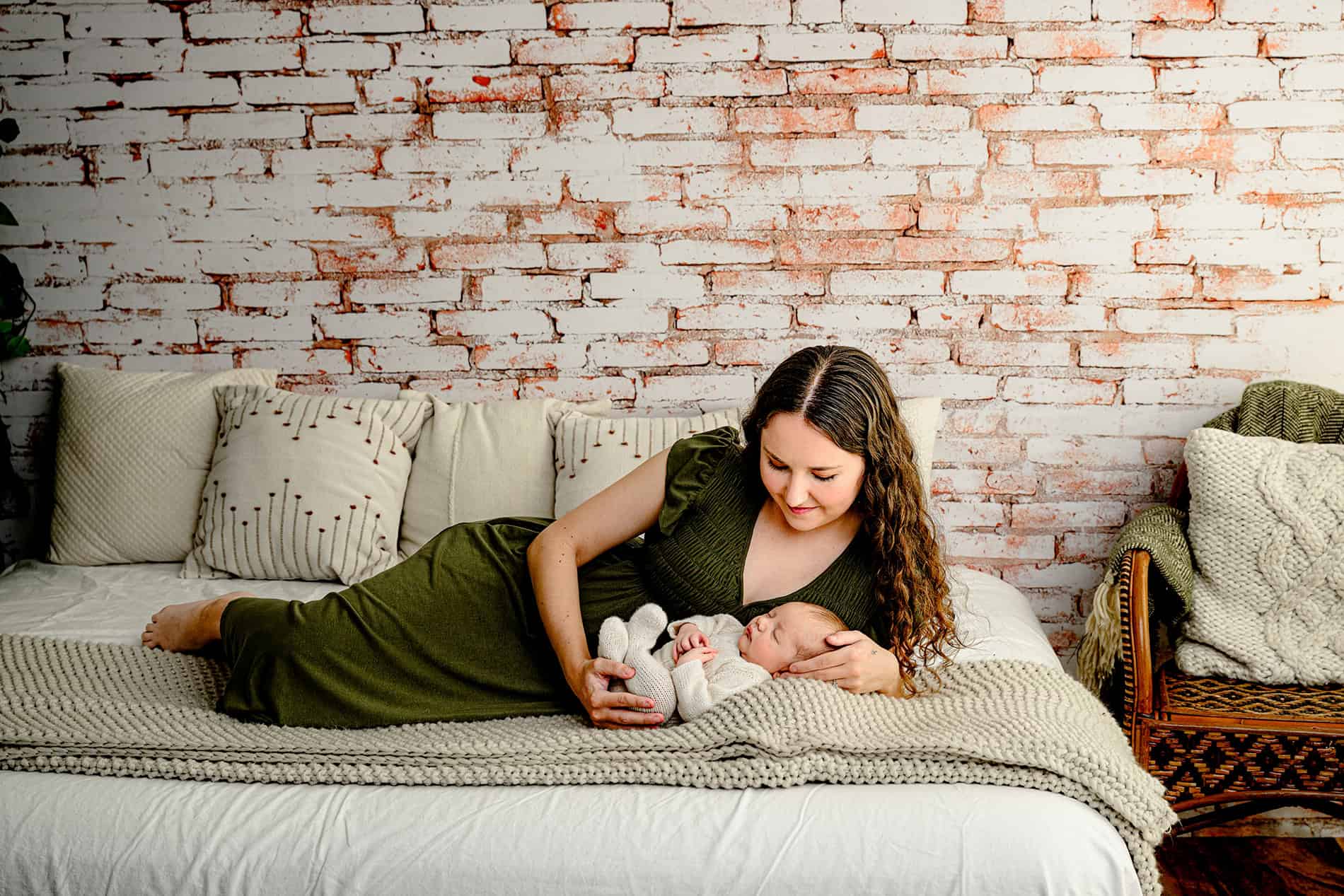 mom laying beside her one month old son in lifestyle newborn set up