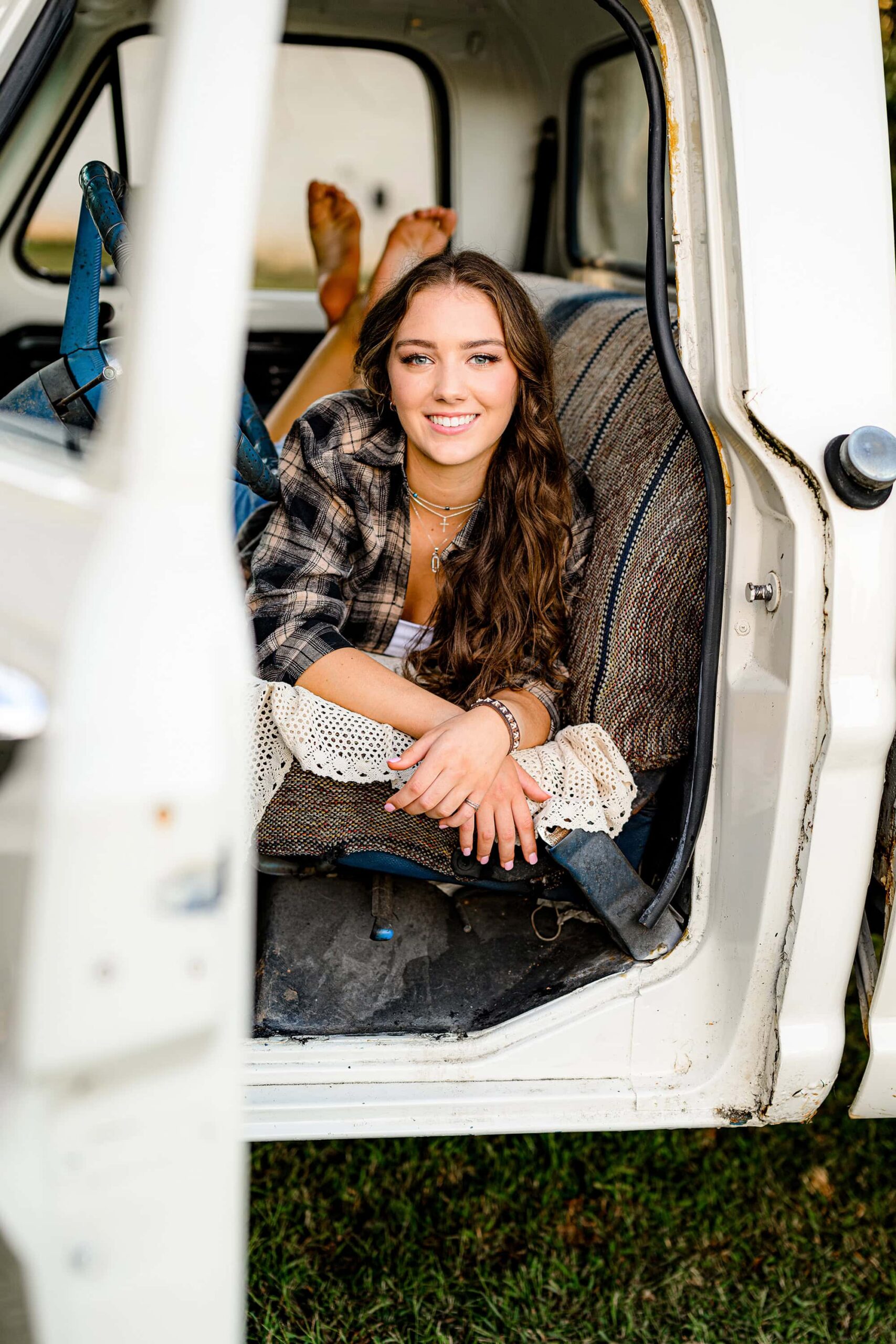 dark hair senior lays on her belly in a truck cab with her natural makeup enhancing her look