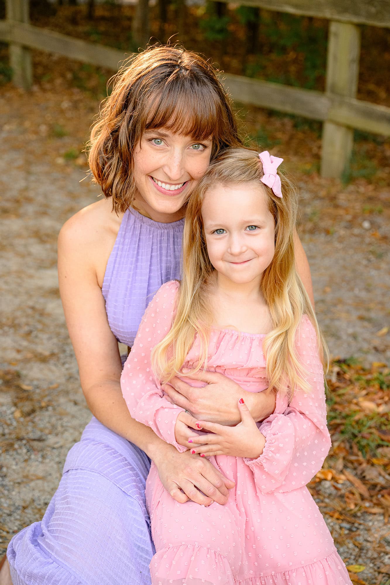 mom cuddling her oldest daugher in a waxhaw park