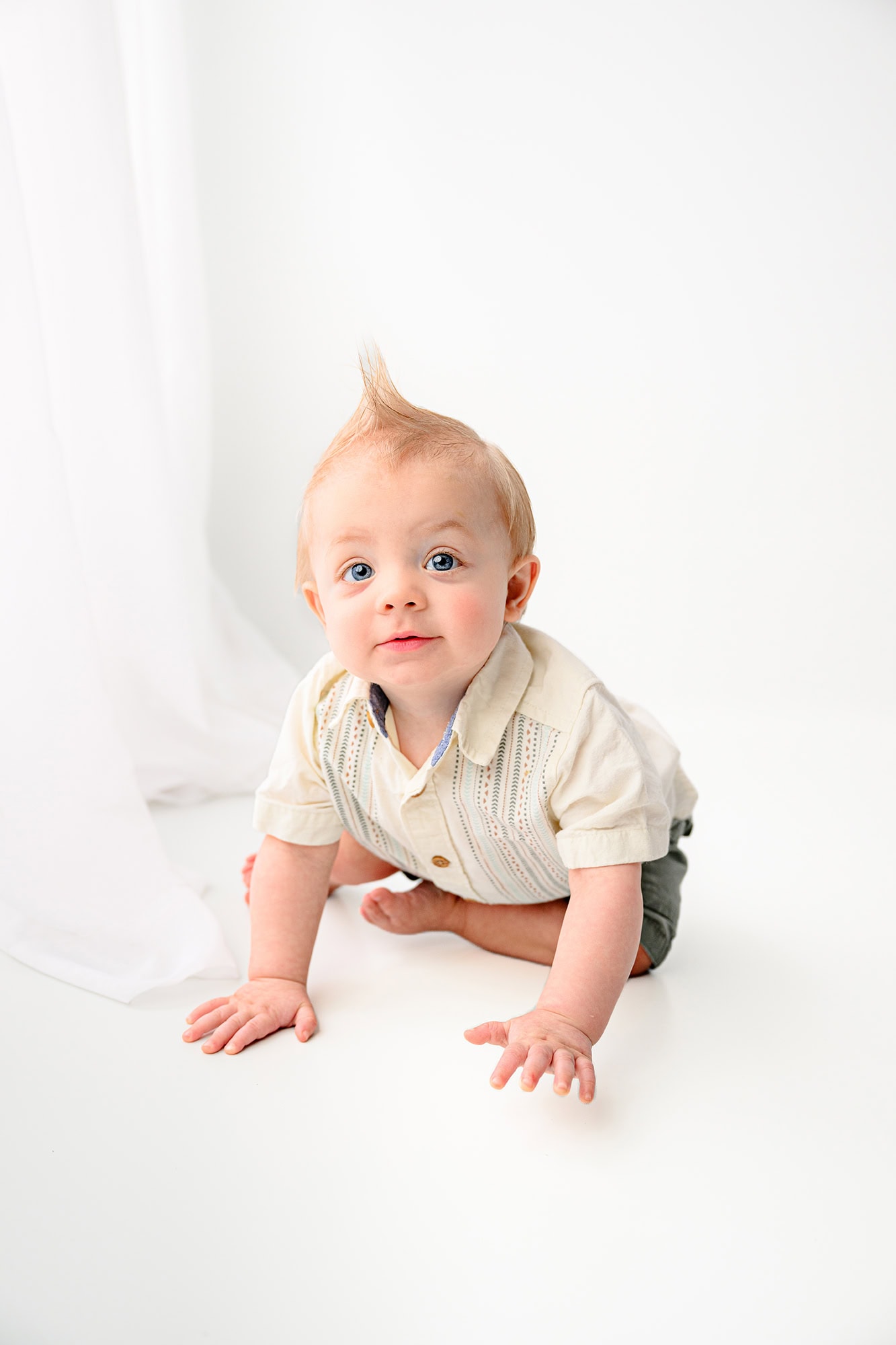 one year old boy sitting in the crawling position for a photoshoot