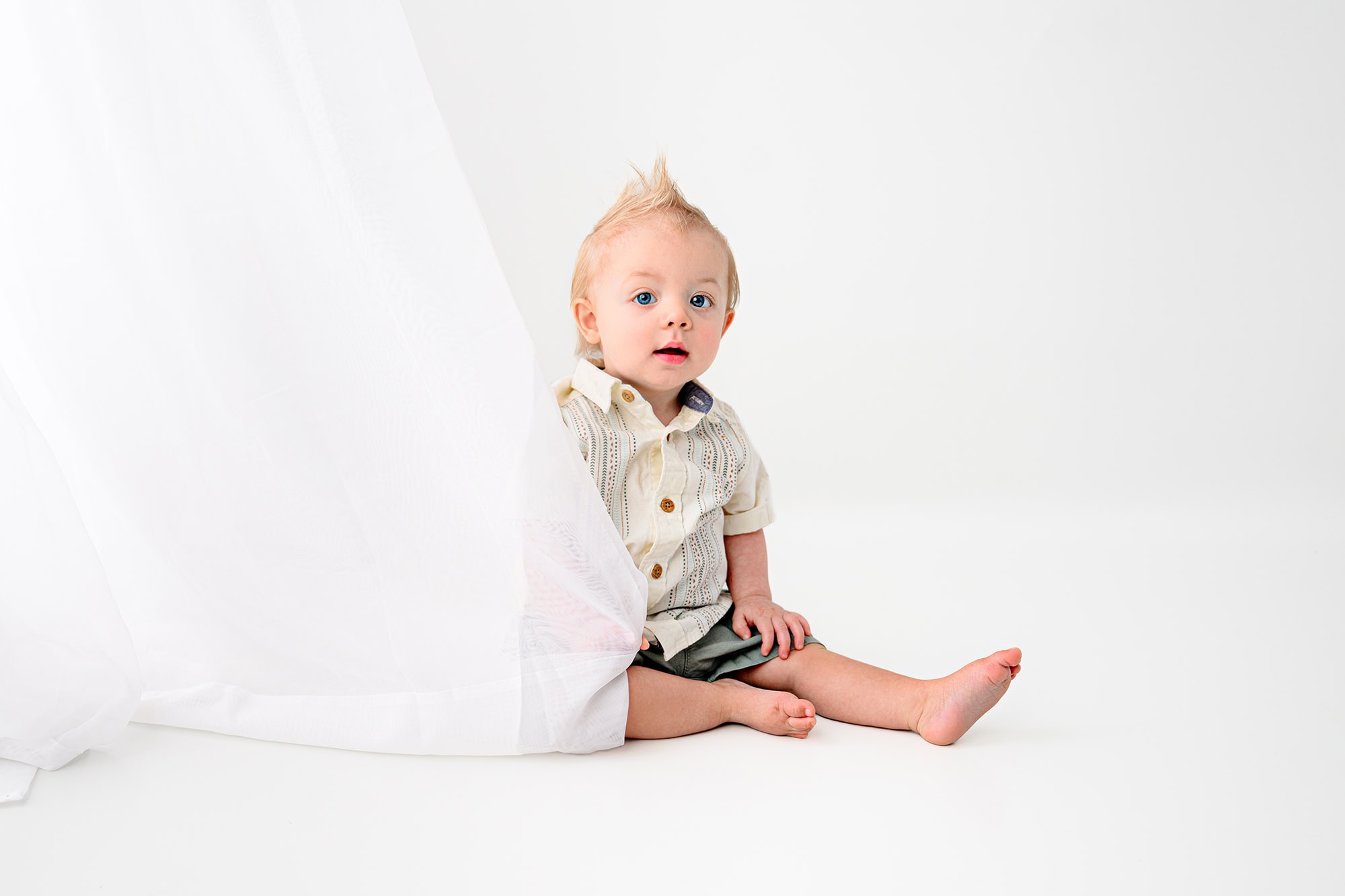 little one year old charlotte boy sitting in a pair of green shorts and cream top