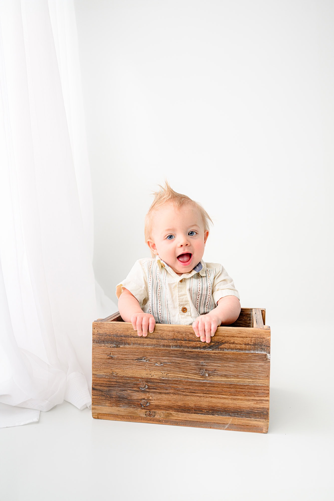 little boy sitting in a brown crate in a white studio set up