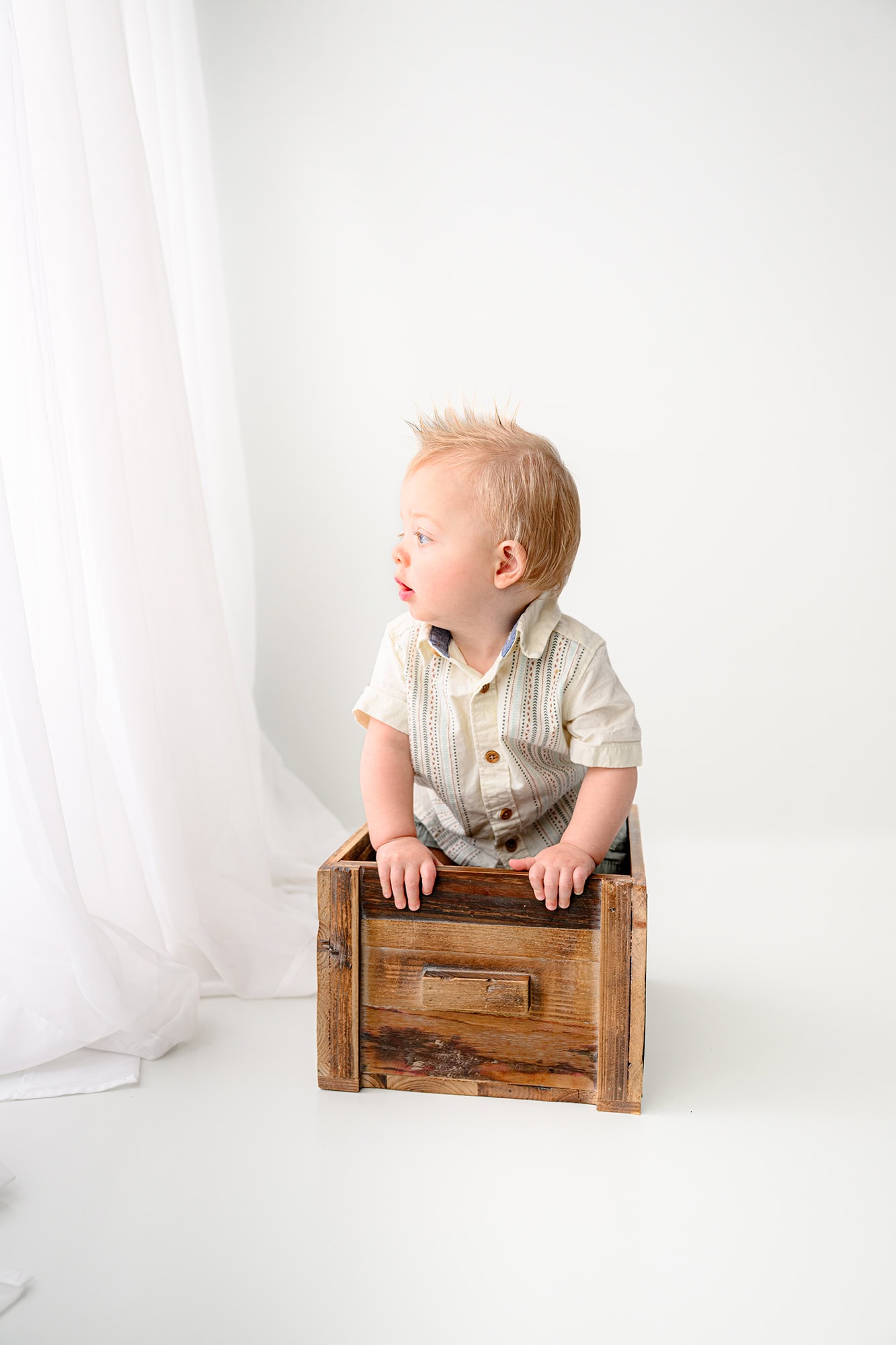little boy sitting in a crate during a  studio photoshoot
