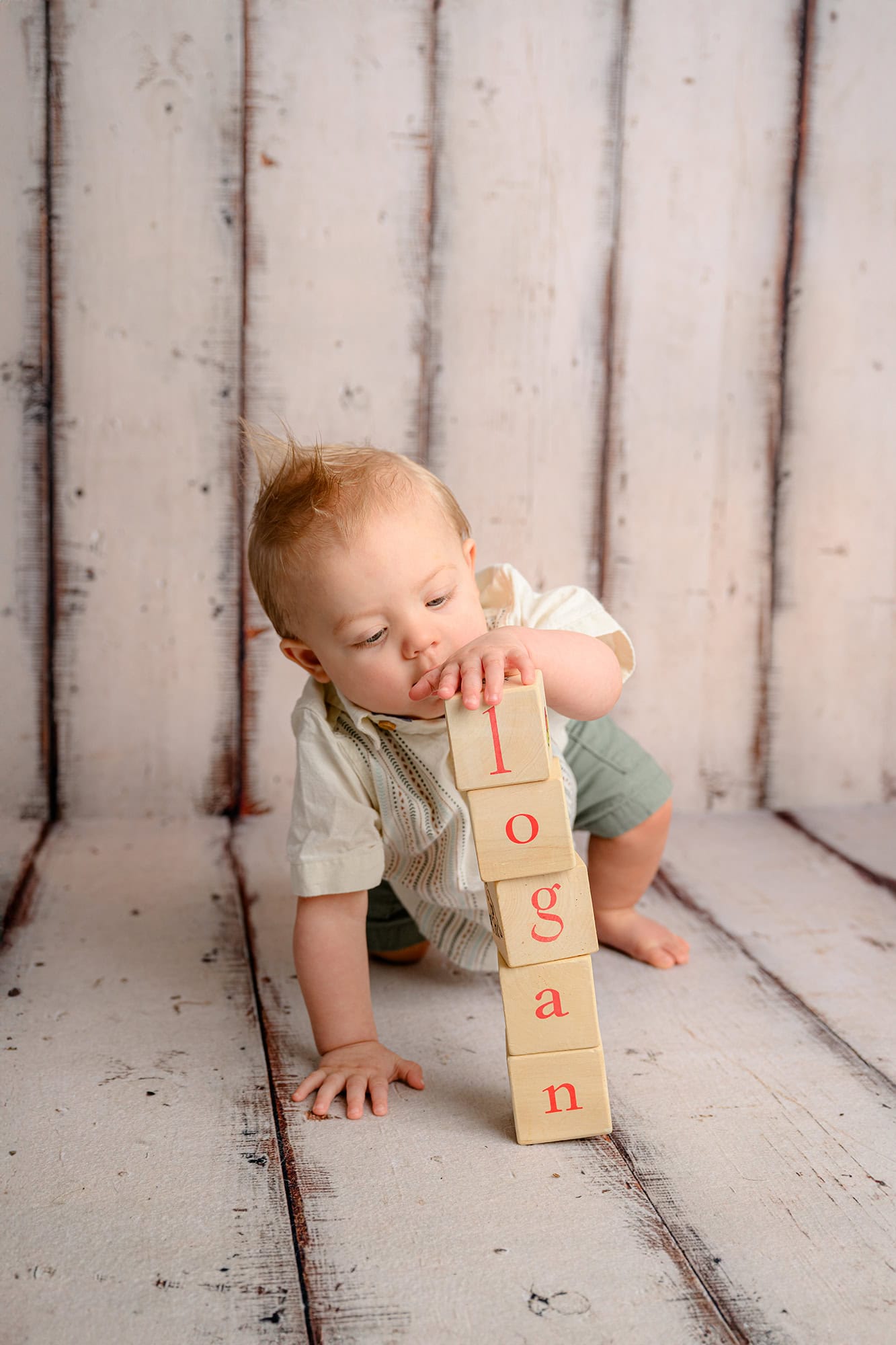 one year old playing with stacked letter blocks 