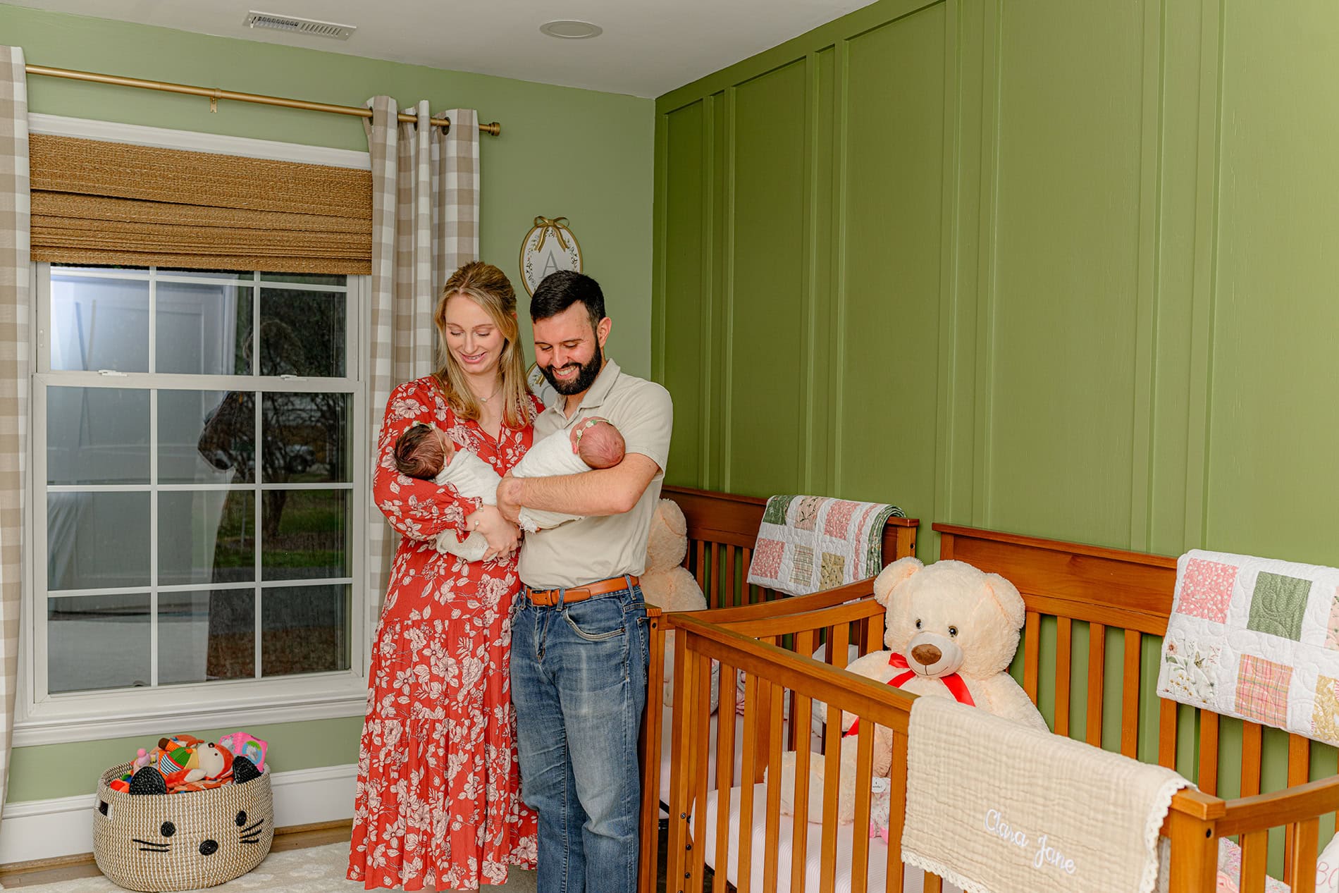 mother and father holding their twin girls in their baby nursery in while standing in their twin girls charlotte home nursery