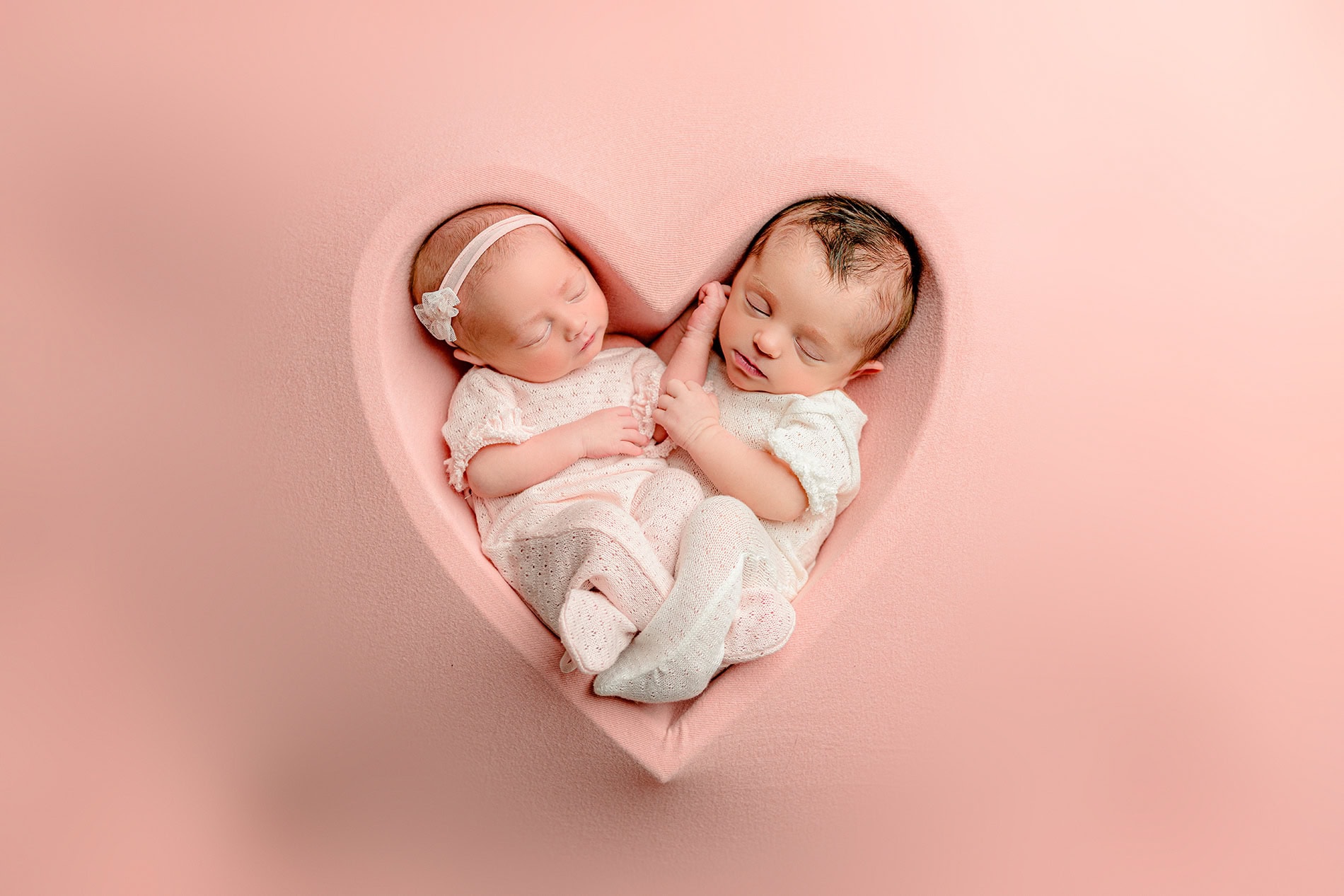 twin baby girls posed in a heart bowl in their lifestyle twin newborn photo session 