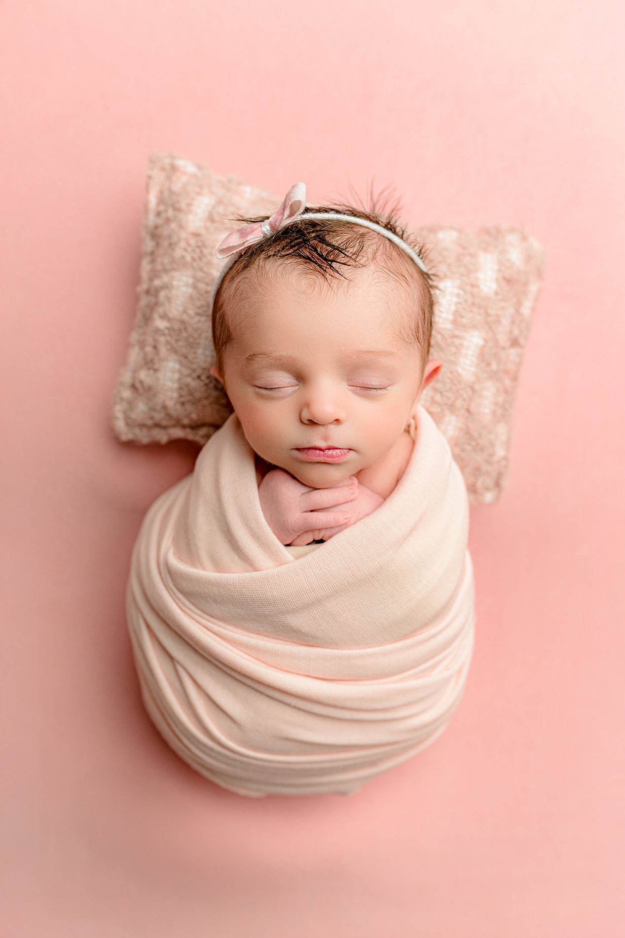 single image of twin newborn daughter wrapped in pink