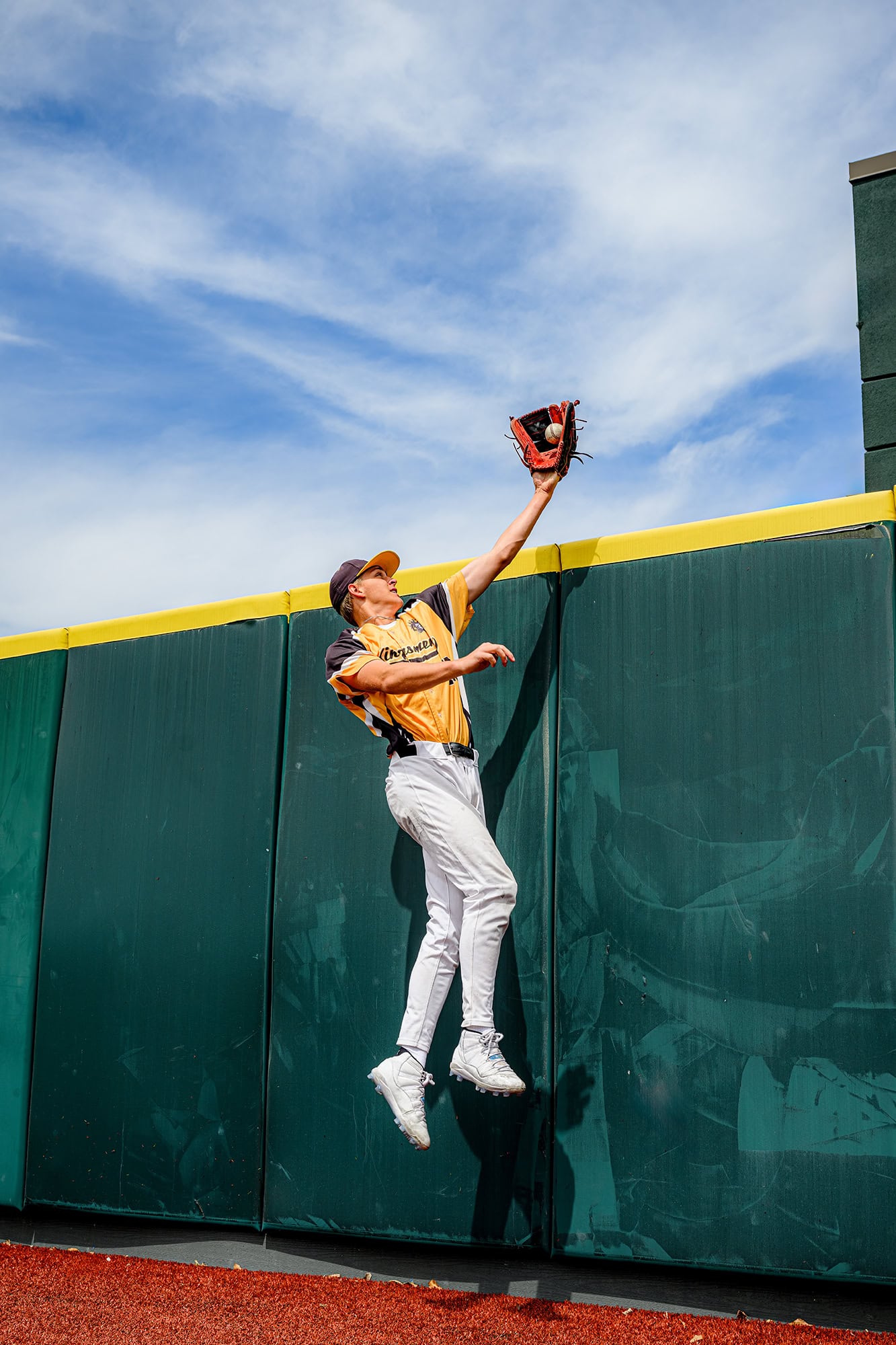 Charlotte baseball senior portraits of outfielder catching a ball over the wall 