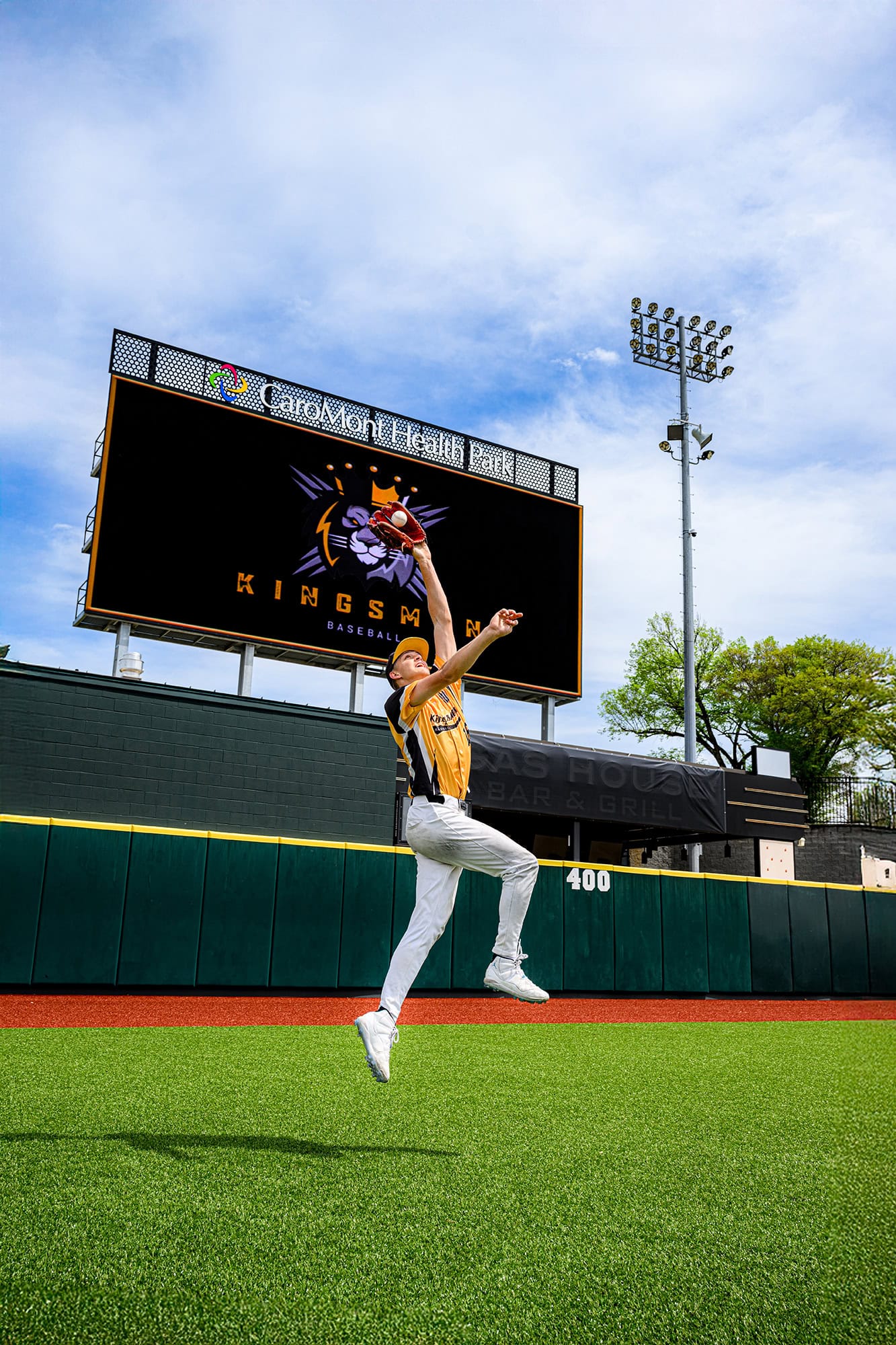 kingsmen academy player jumping on field to catch a ball for baseball senior portraits