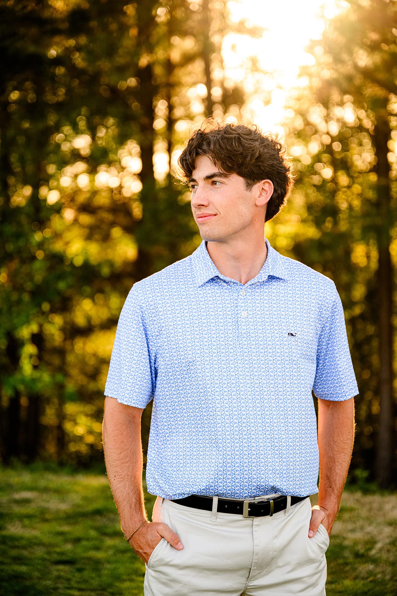dark hair charlotte senior wearing a blue shirt and shorts during his senior golf portraits