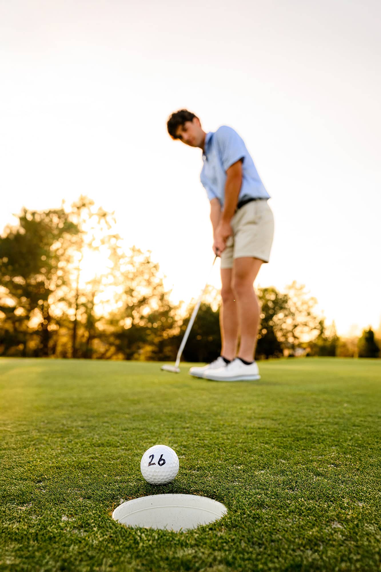charlotte senior dressed in blue shirt and shorts putting a class of 2026 golf ball 