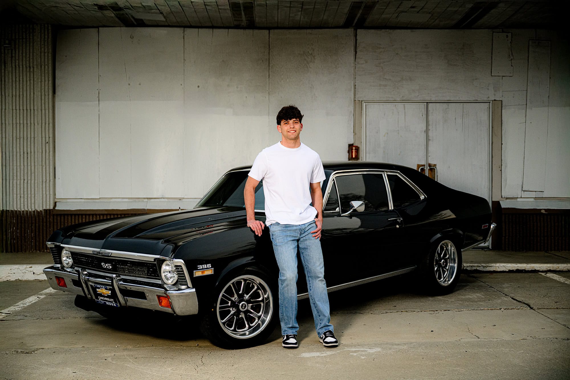 dark hair charlotte senior wearing white shirt and jeans leaning against a black classic car