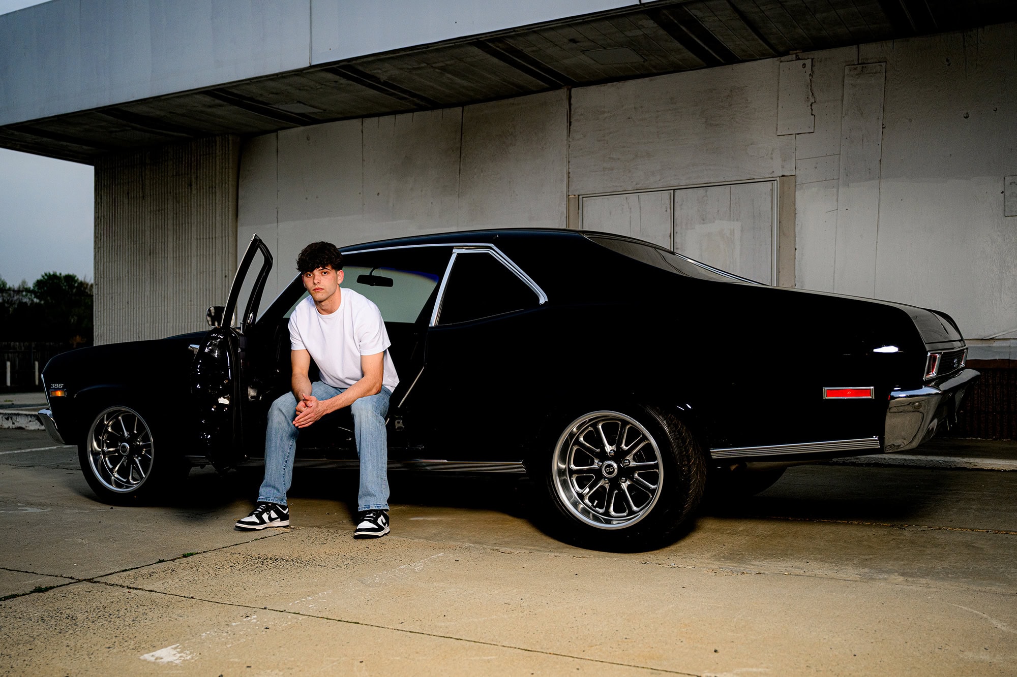 porter ridge sitting in a classic car wearing jeans and t shirt for his senior photos