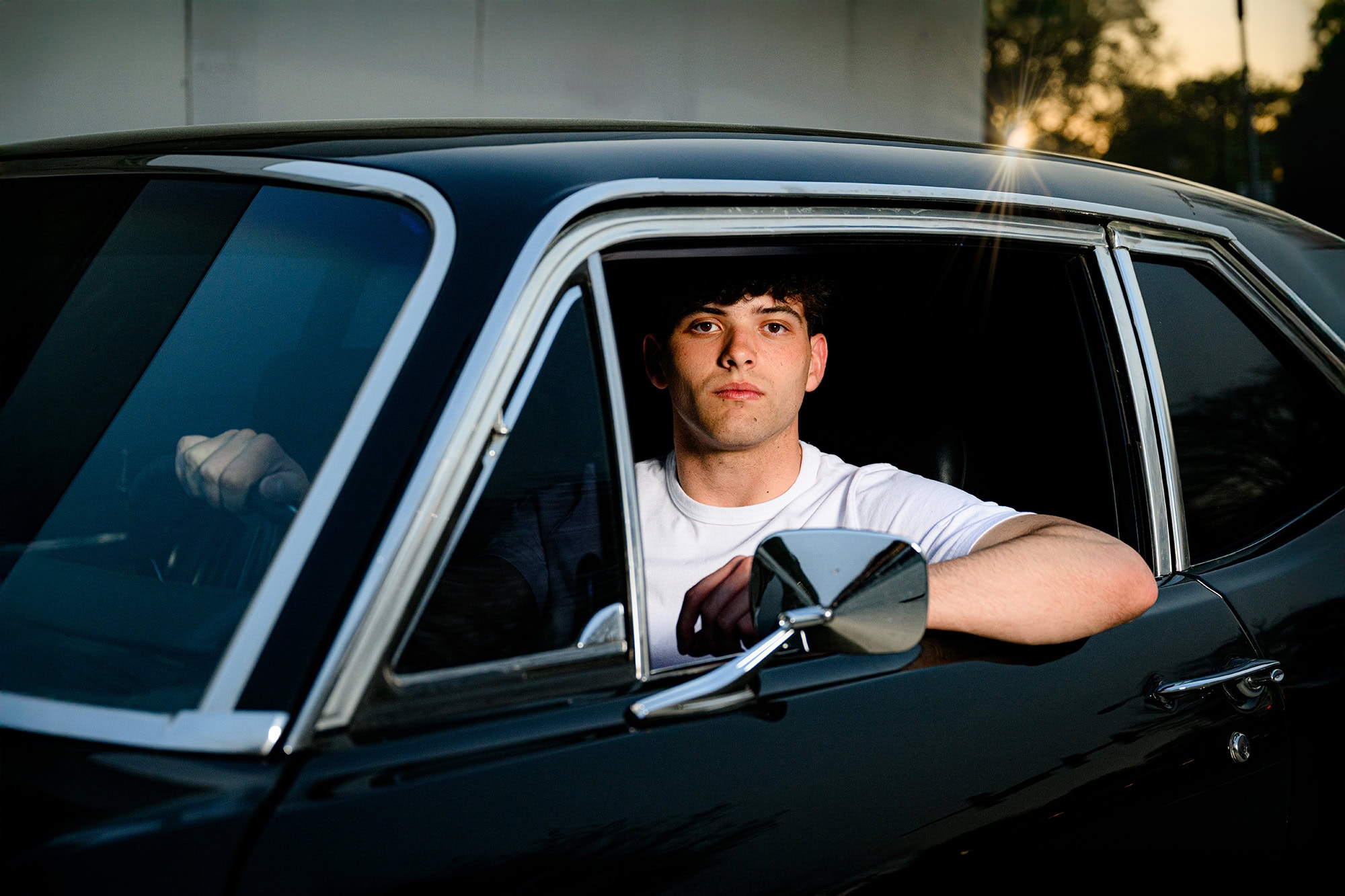 Dark hair charlotte senior sitting in classic vintage car for his senior photos