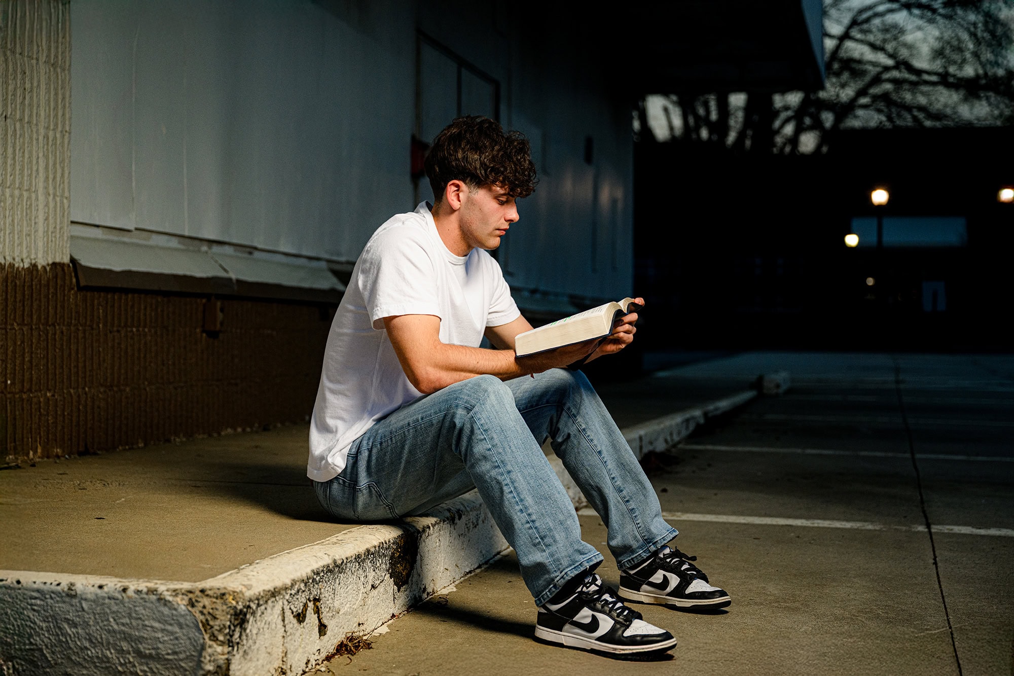 senior photos of graduate wearing jeans and t shirt holding his bible