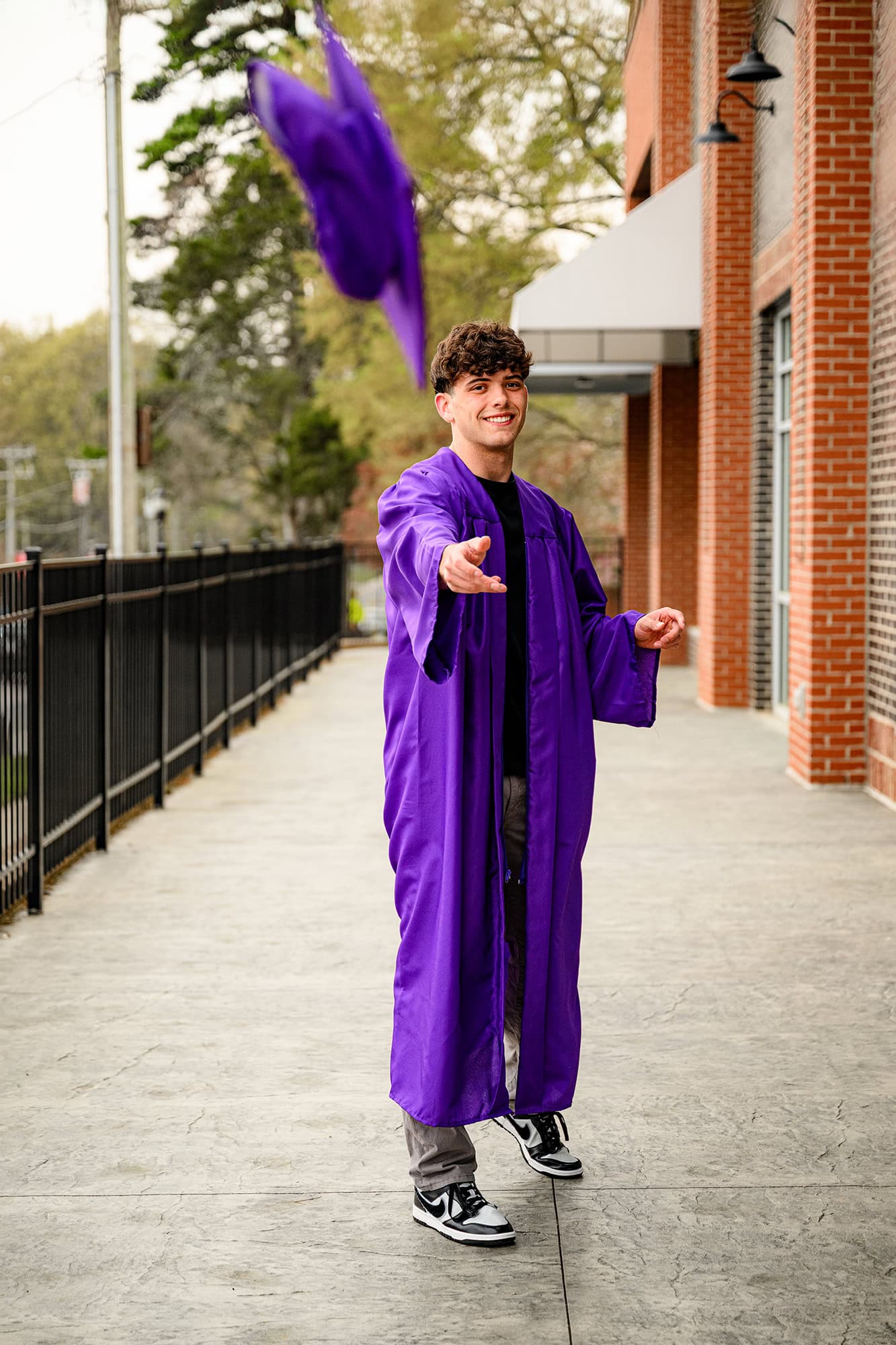 charlotte senior wearing black shirt and jeans and tossing his cap and gown