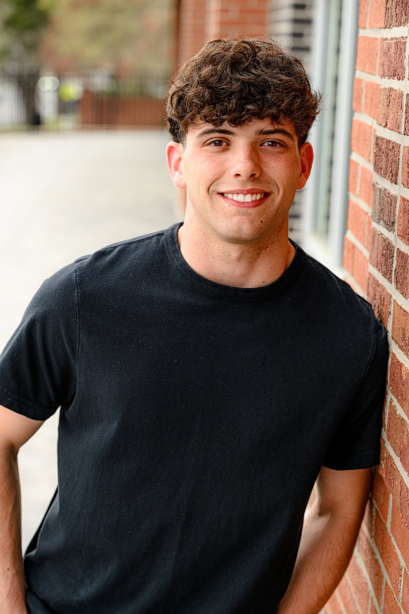 porter ridge graduate leaning against a brick wall wearing a black shirt
