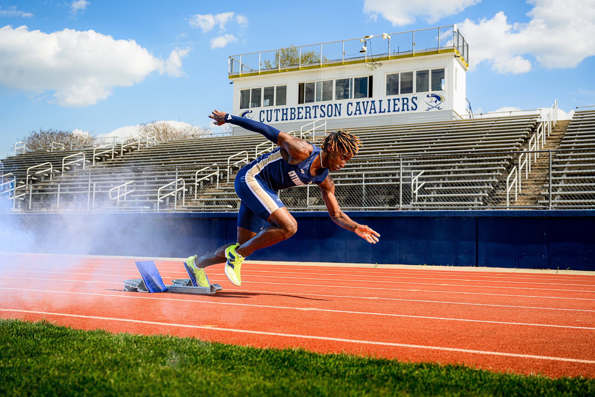 cuthbertson high school track athlete in starter on his home high school track for his senior photos wearing his blue home uniform
