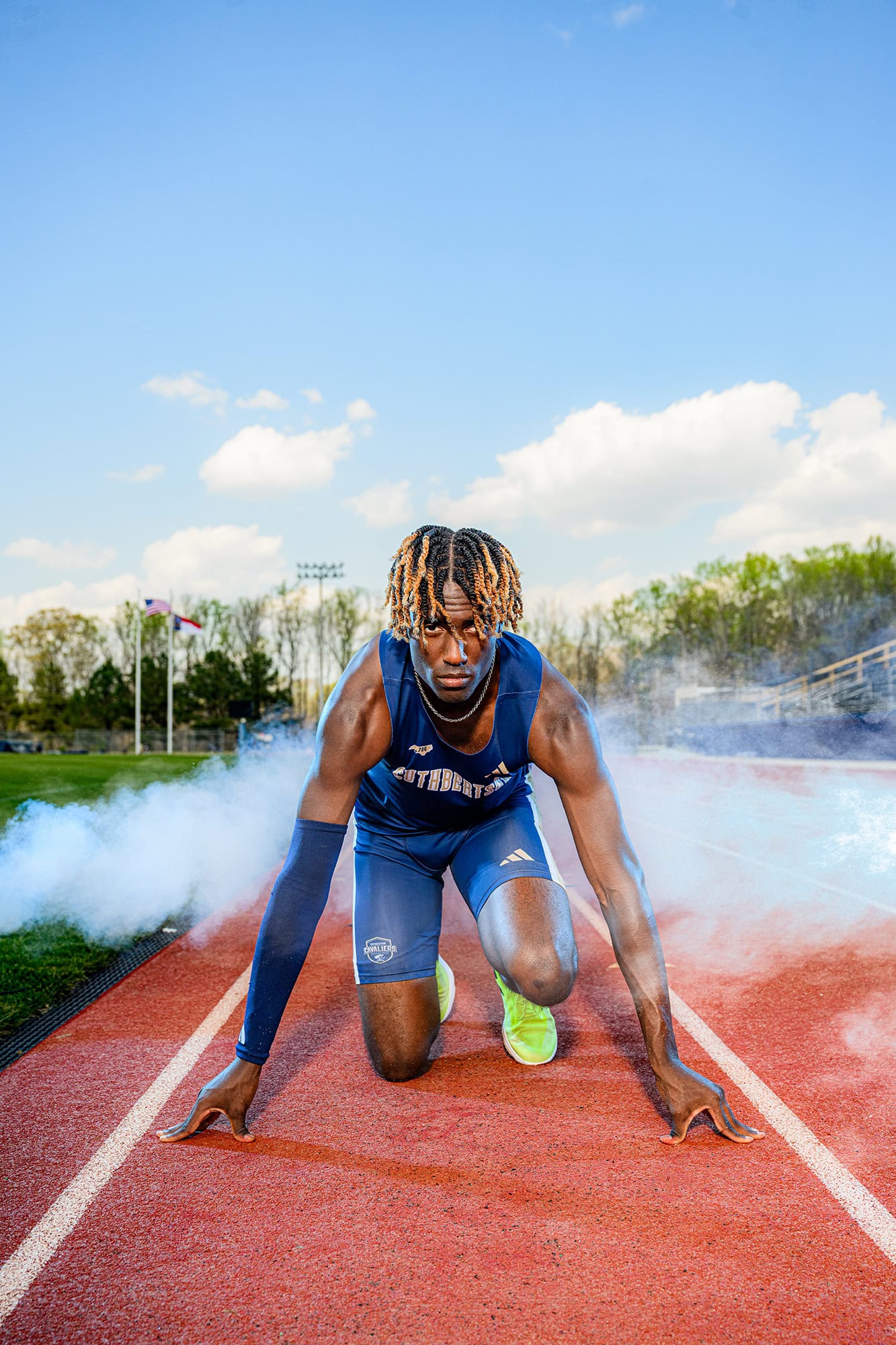 track and field senior photo of charlotte graduate wearing a blue uniform in runners stance