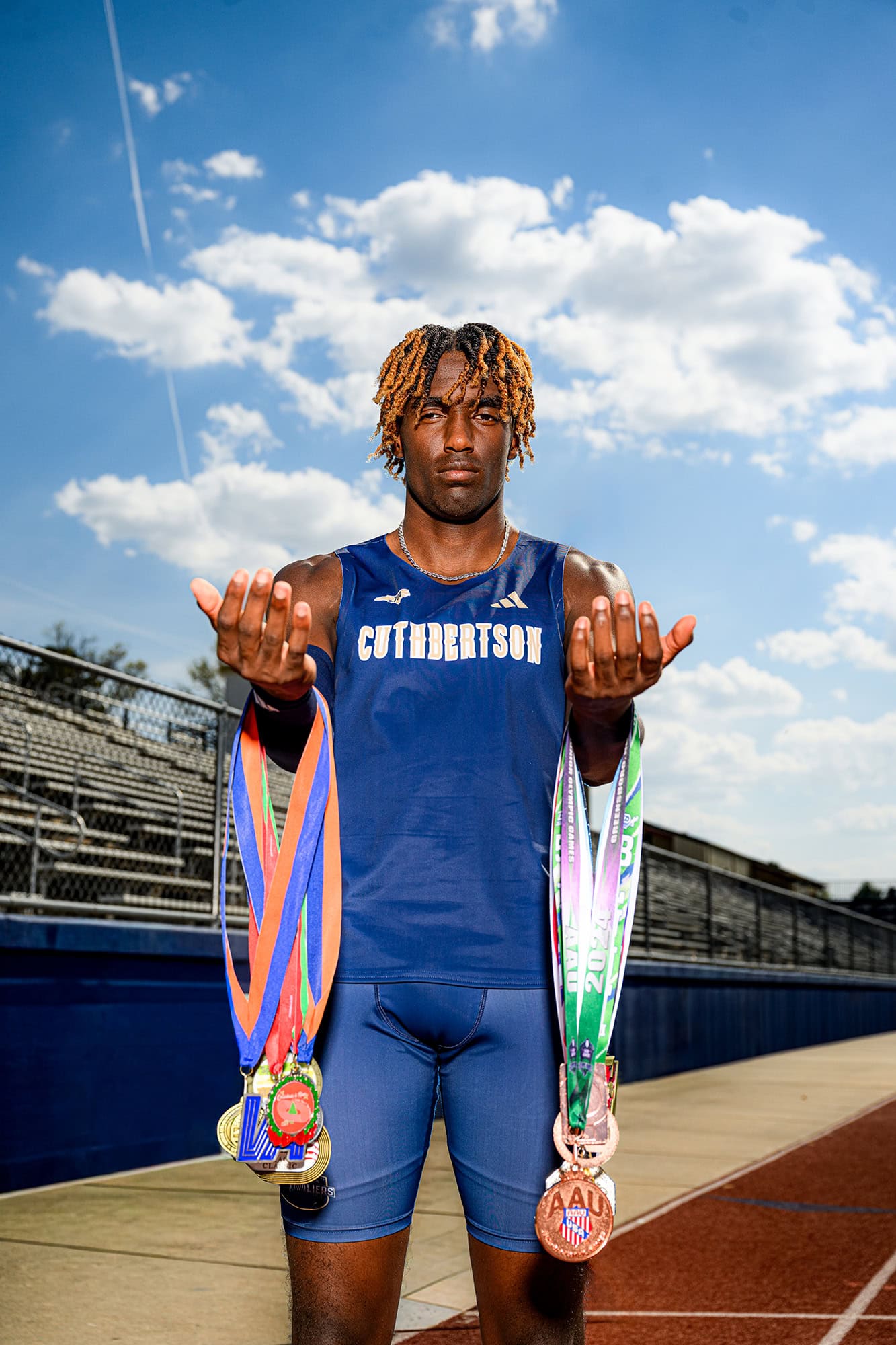 CHS track athletes standing in a charlotte high school stadium holding his sports medals