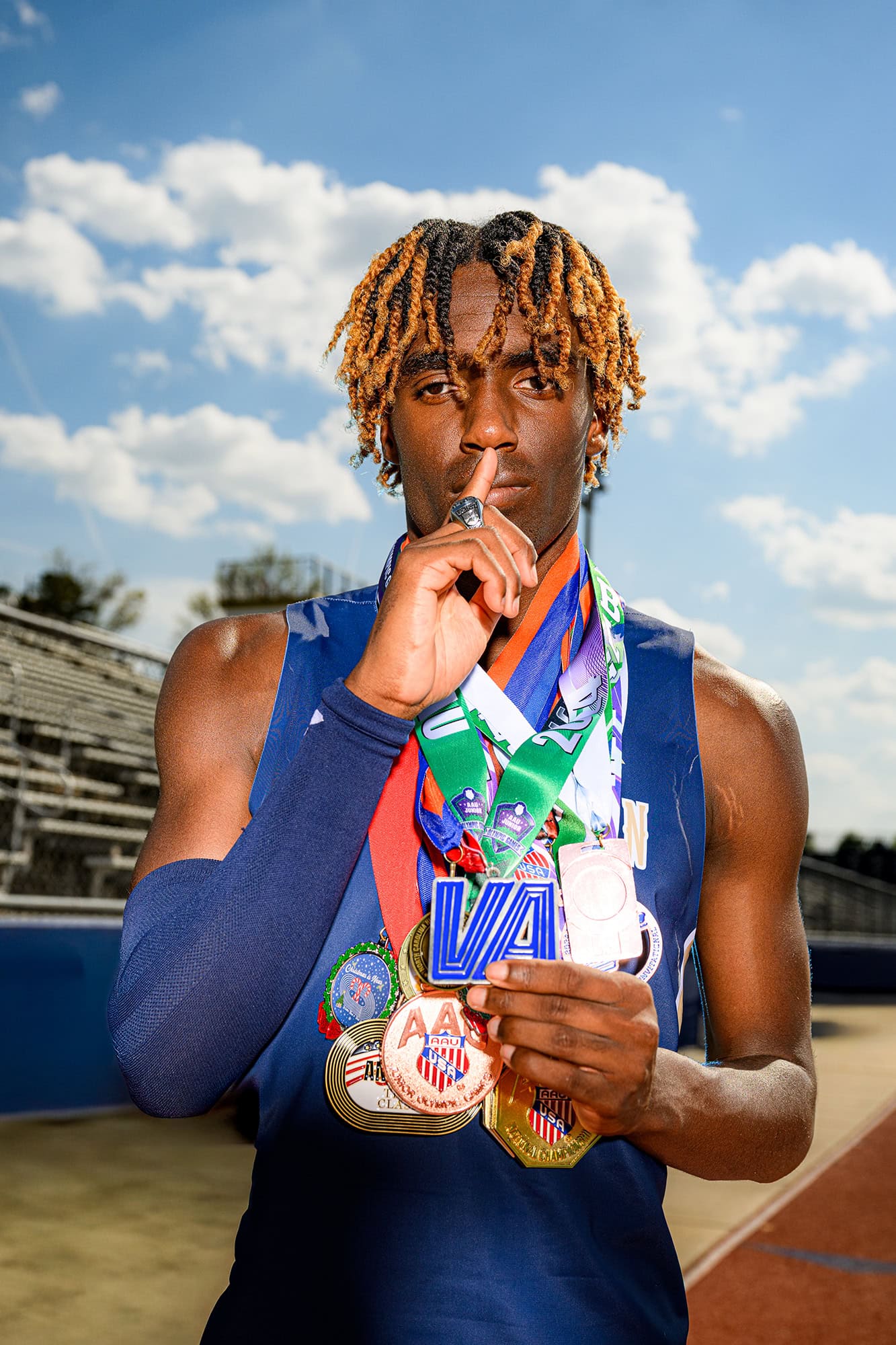 CHS track athlete photos wearing his senior medals giving the shhh pose