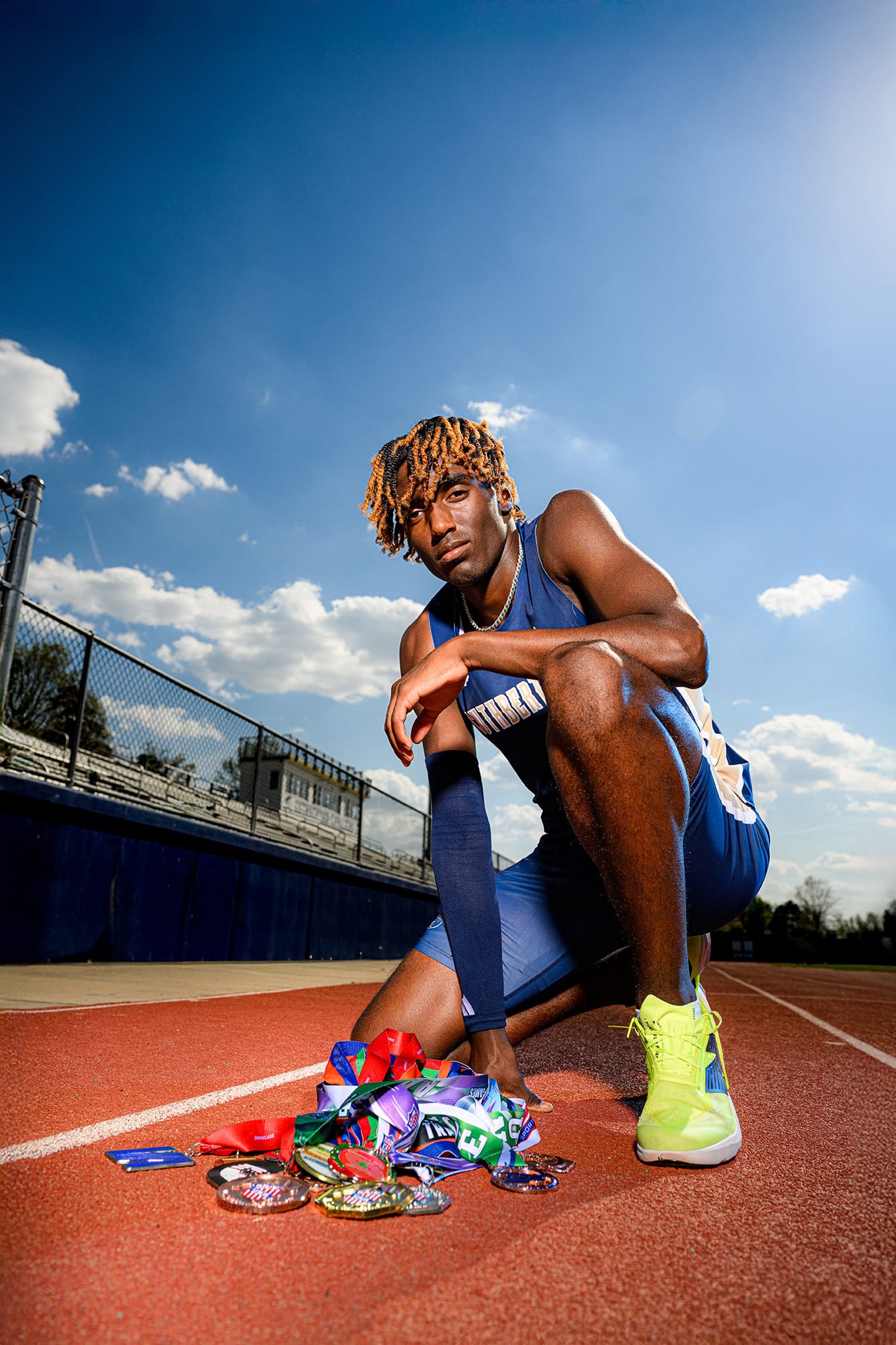 dramatic sports image of a track and field athlete sitting next to his medals on the charlotte track 