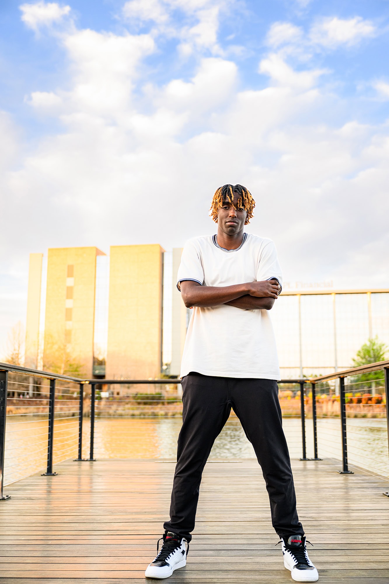 charlotte senior wearing white shirt and pants with his arms crossed standing on a boardwalk