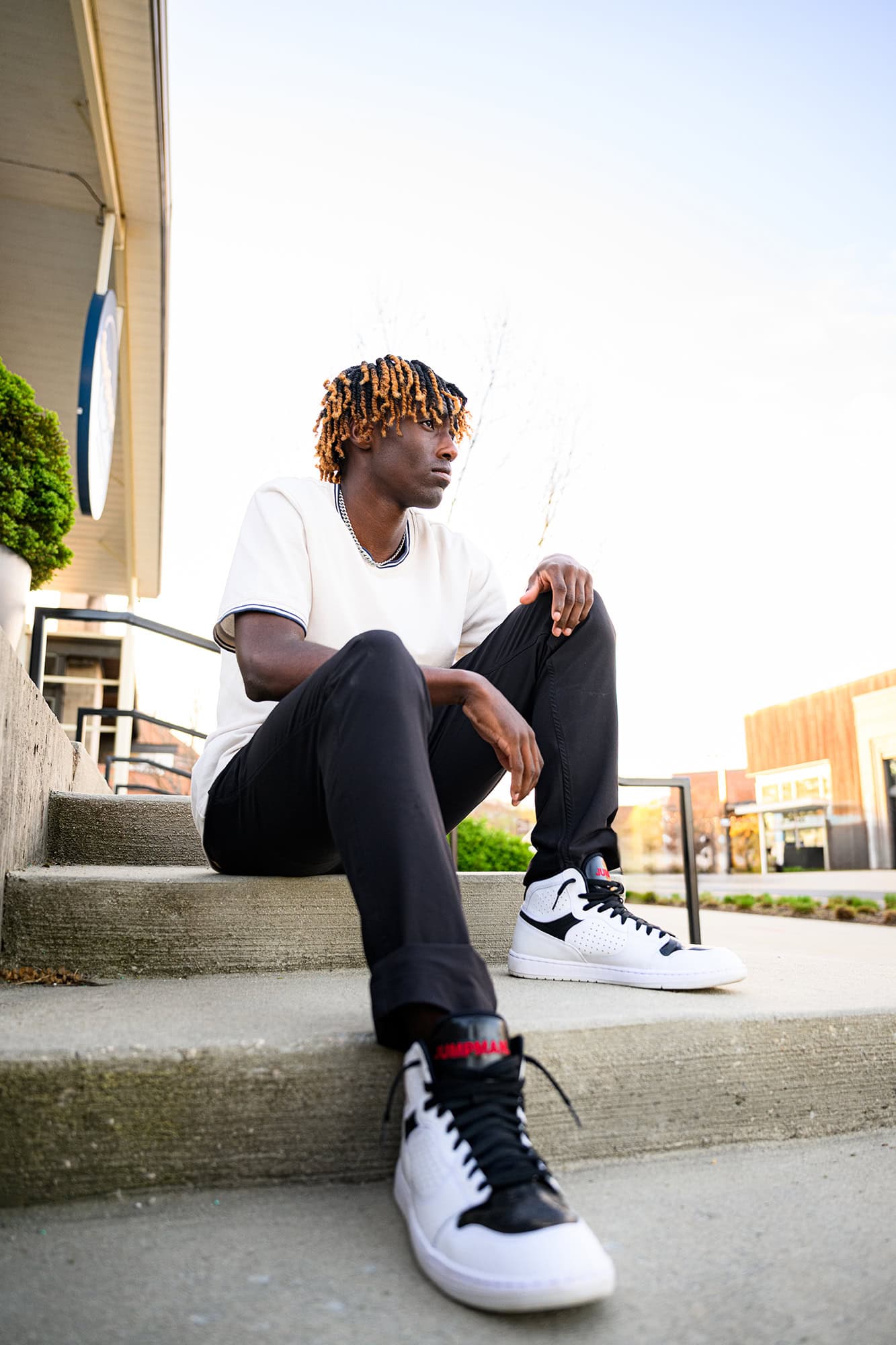 charlotte grad poses sitting on a set of steps with his nike shoes in forefront 