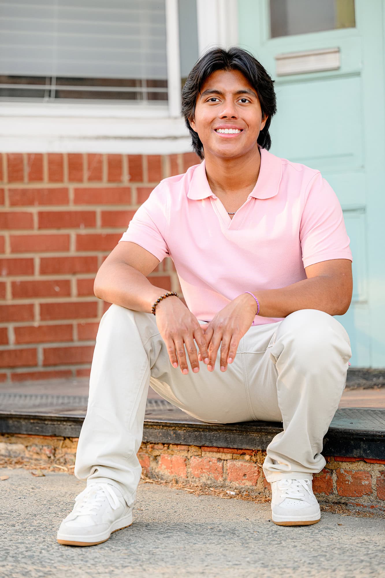 morning photo in downtown waxhaw of senior boy sitting on the step wearing a pink shirt
