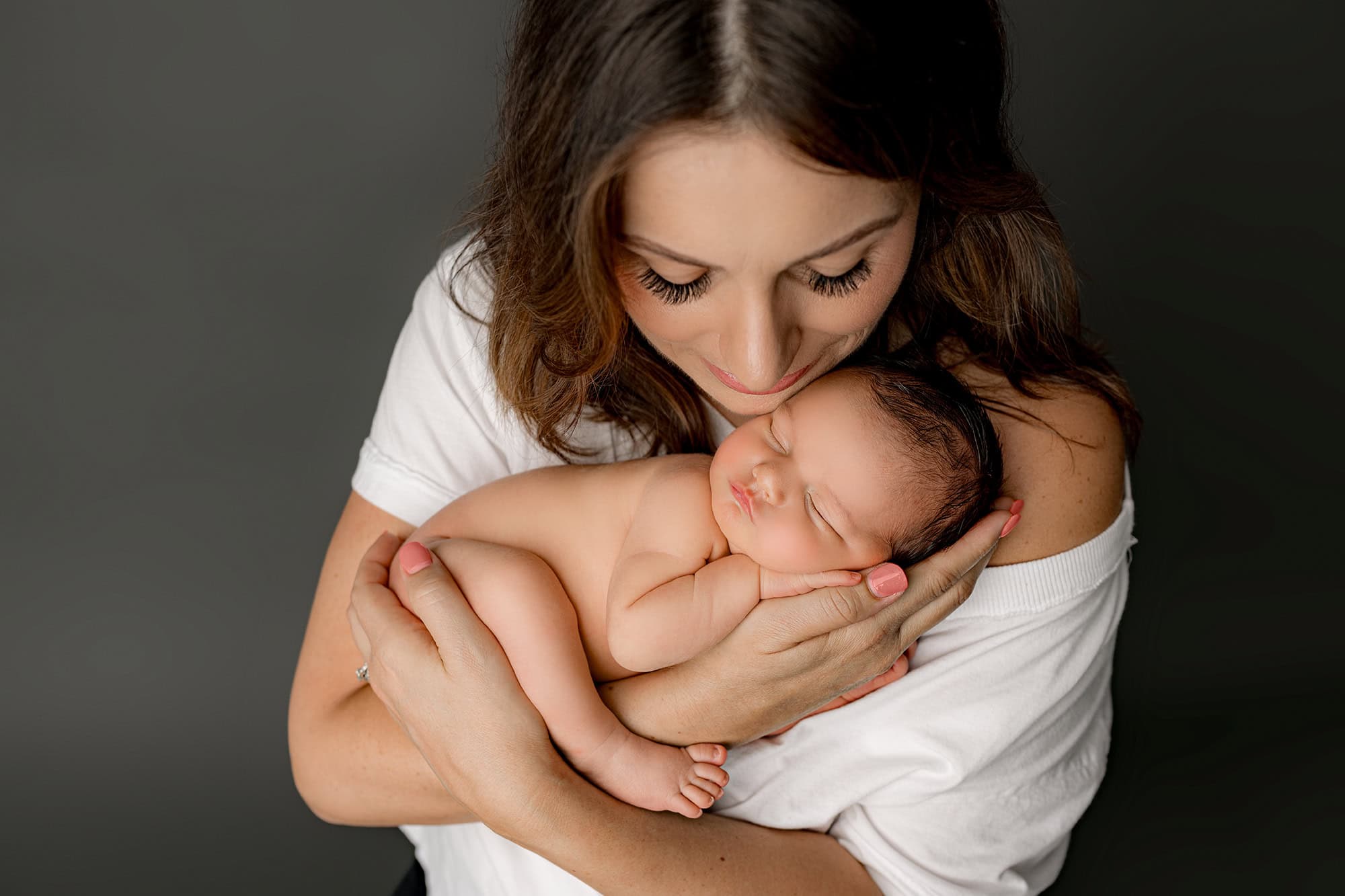 newborn charlotte mom holding her newborn son posed in her hands